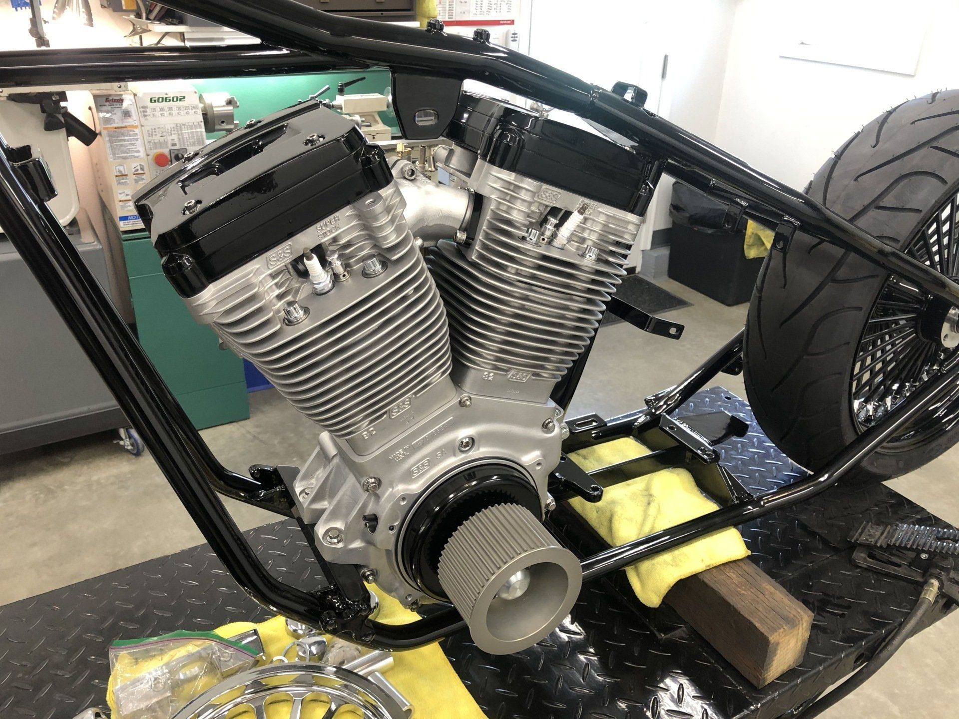 A motorcycle engine is sitting on a table in a garage.