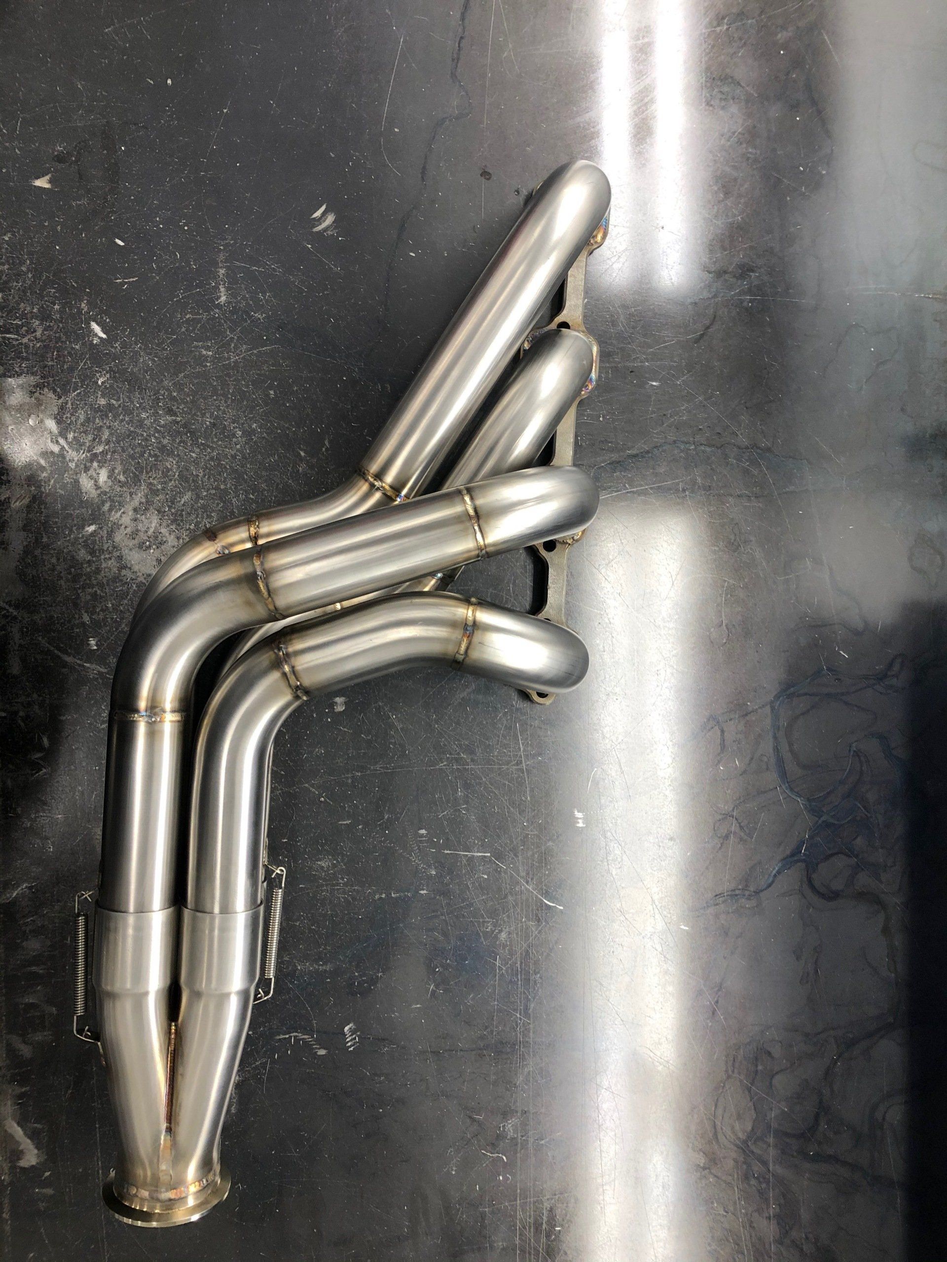 A stainless steel exhaust pipe is sitting on a black surface.
