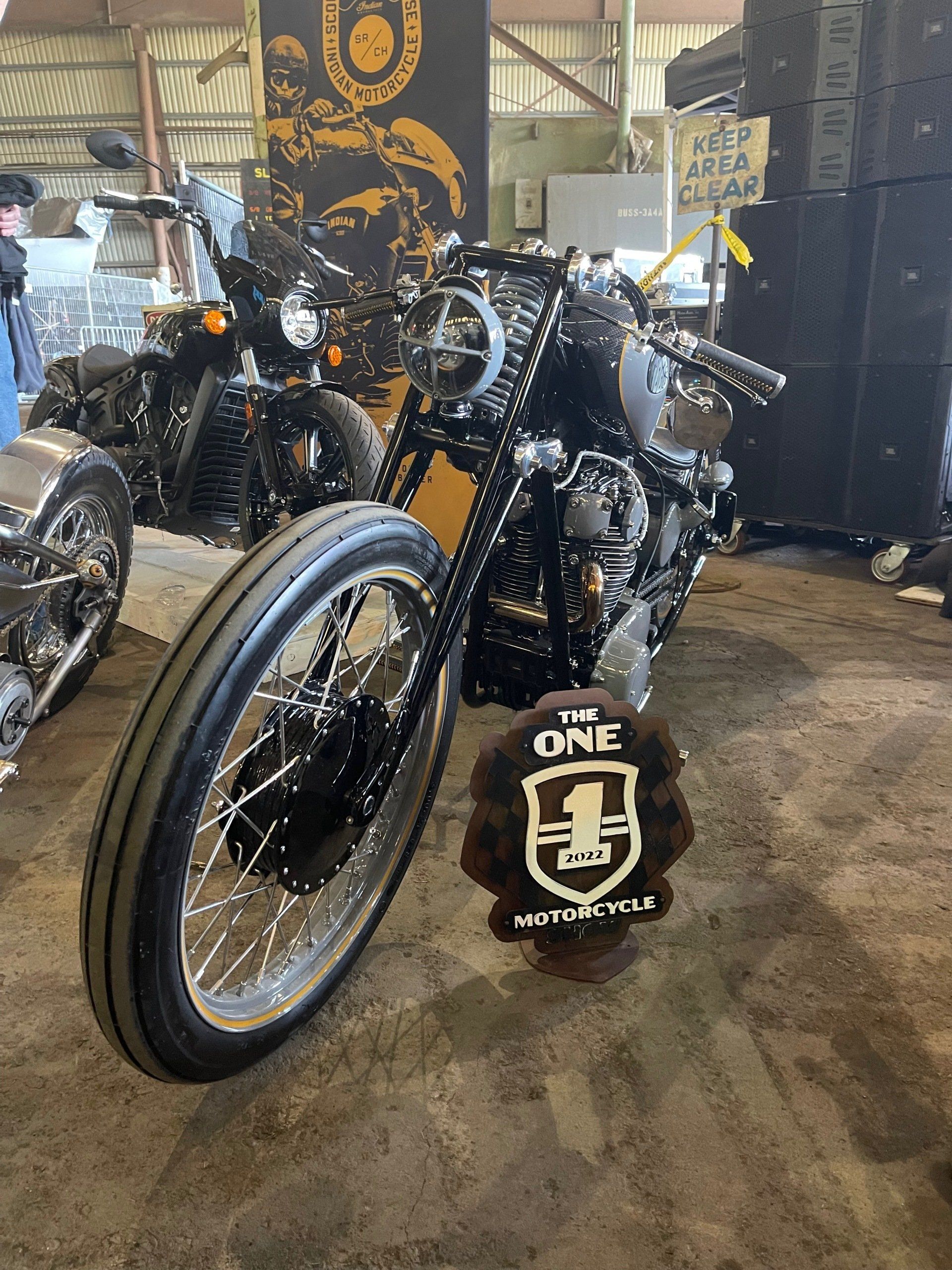 A black motorcycle is parked next to a sign that says the one.