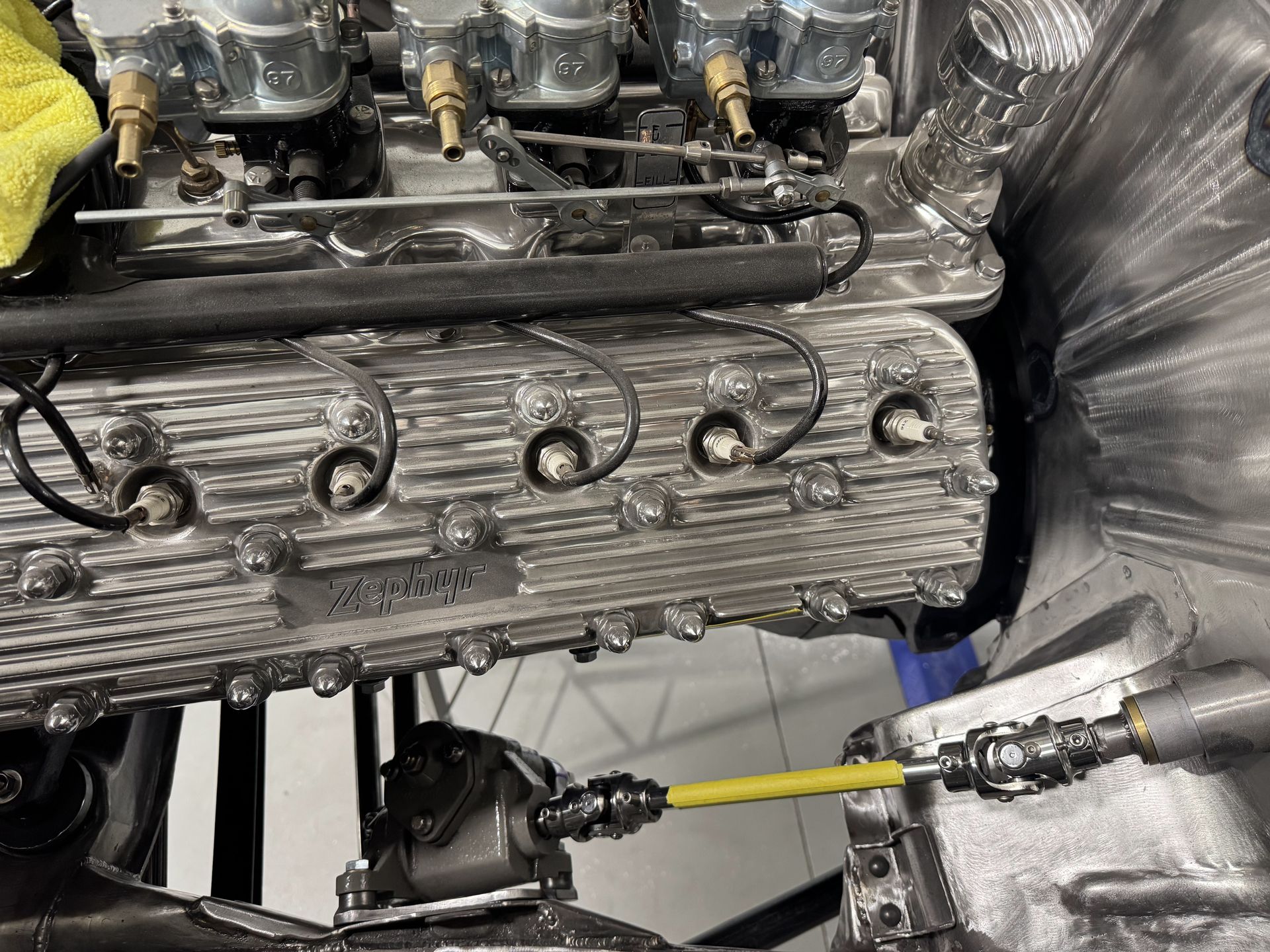 A close up of a car engine with a yellow hose attached to it.