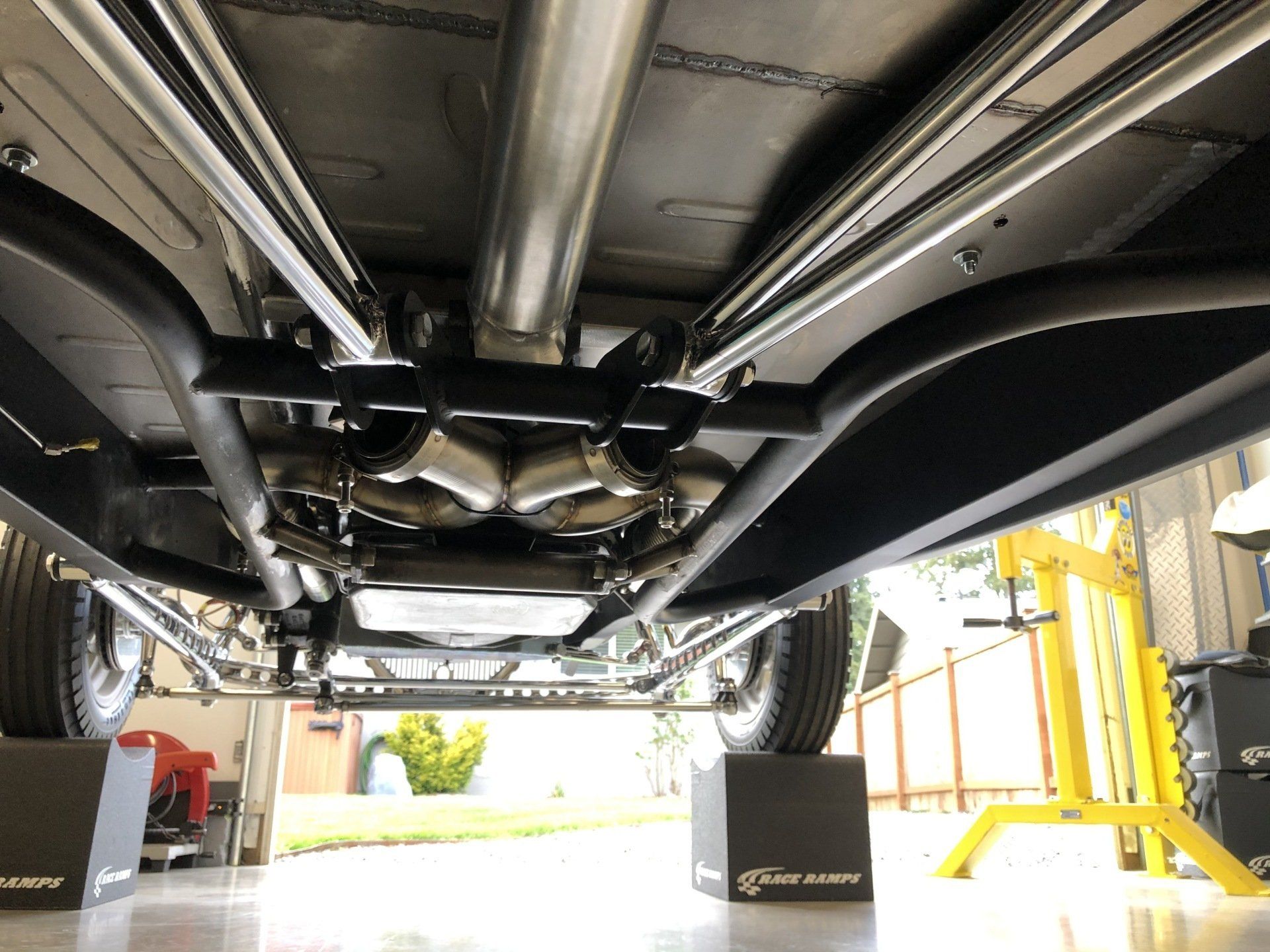 The underside of a car is shown in a garage.