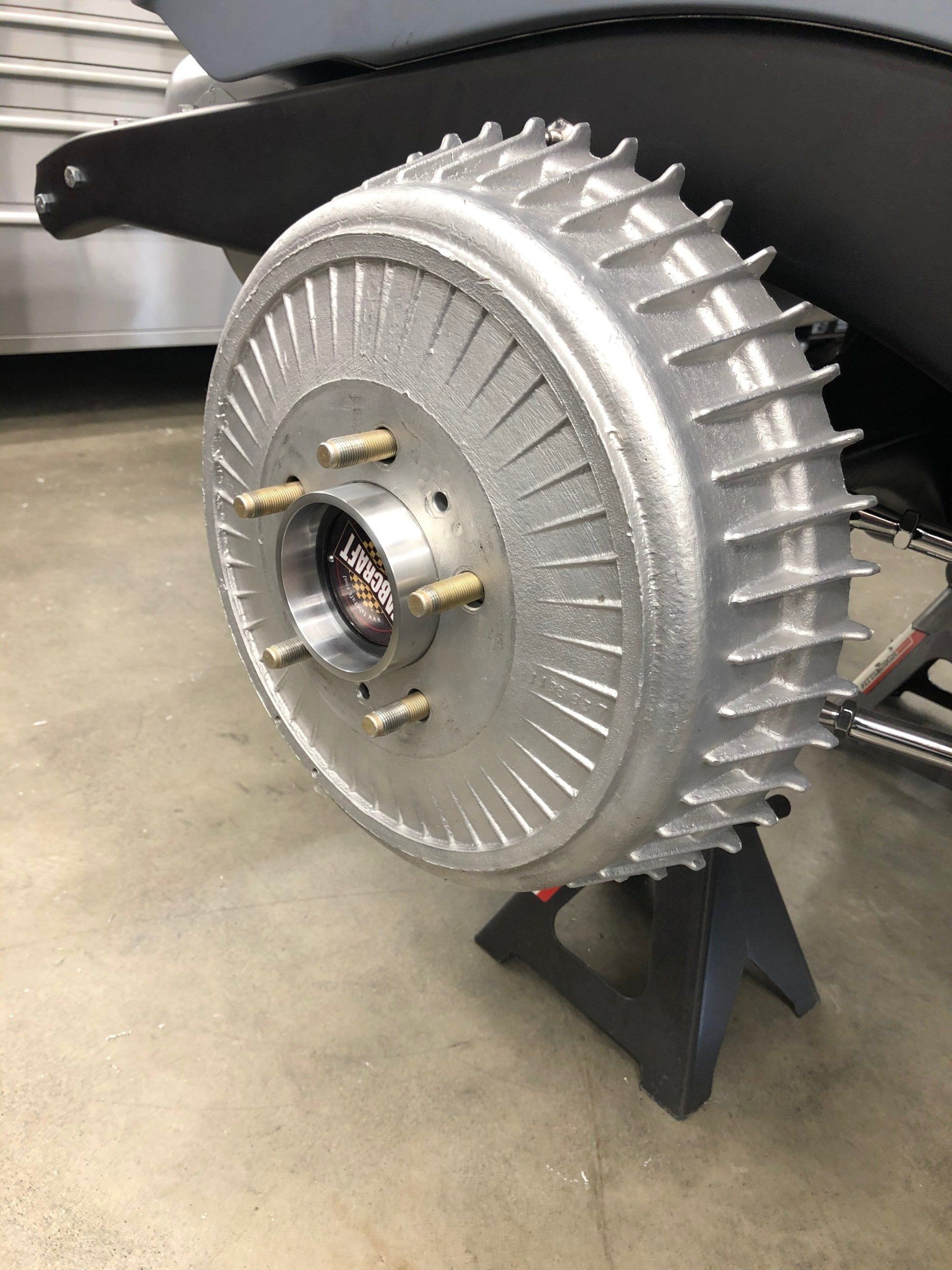 A close up of a brake drum on a car on a stand.