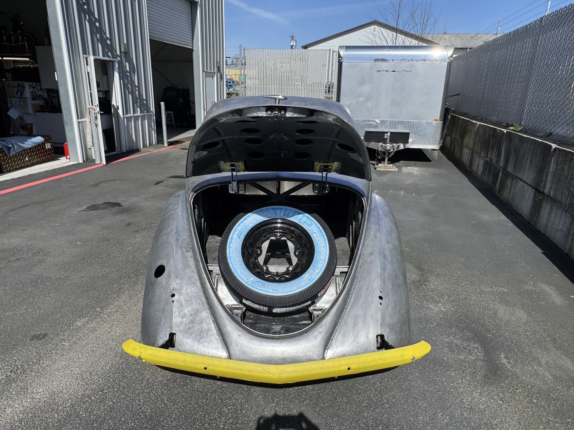 A car with the hood up is parked in a parking lot.