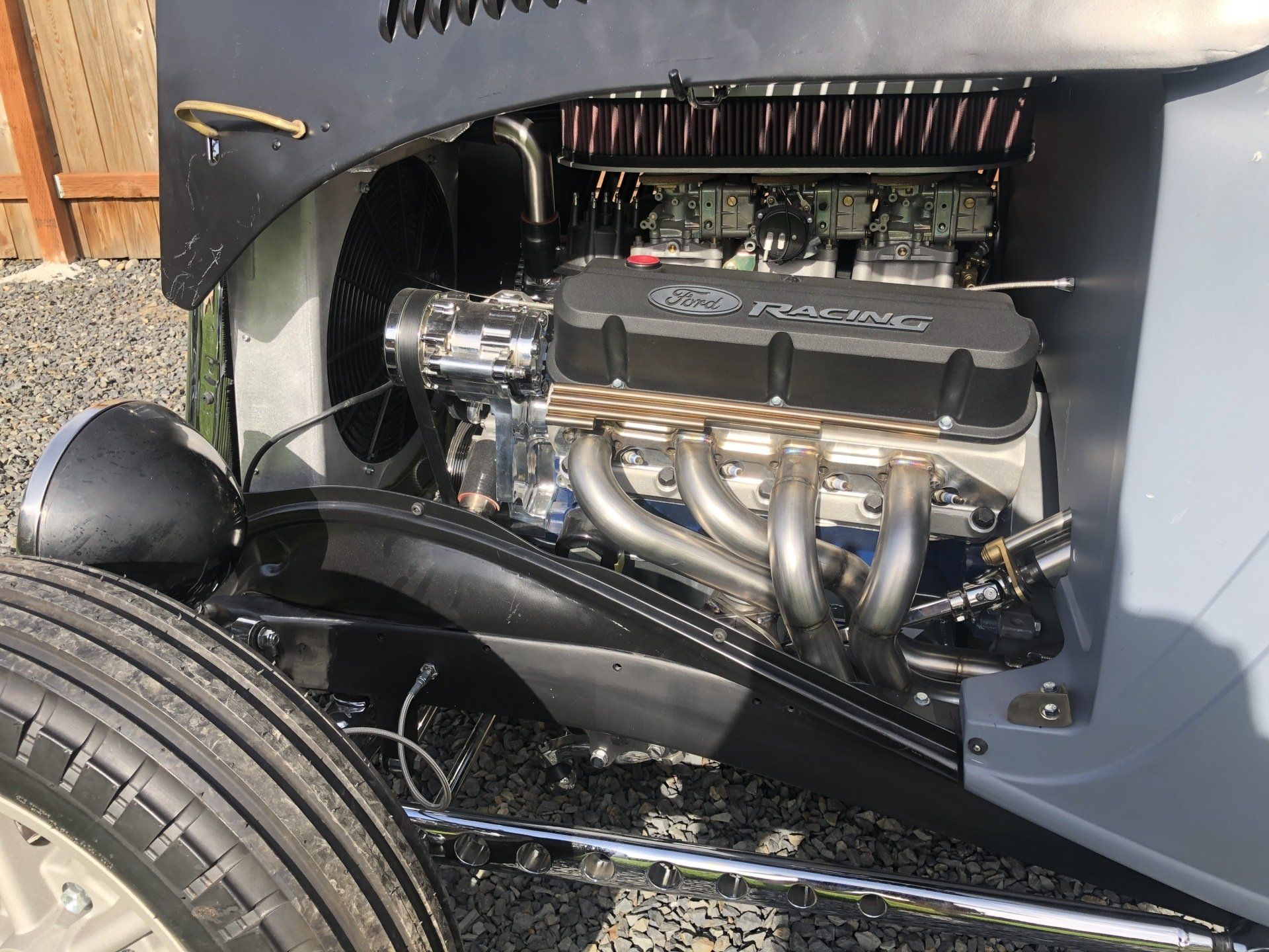 A close up of a car engine with a tire in the foreground.