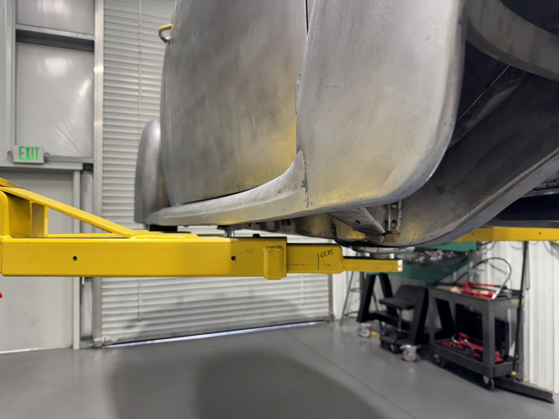 A car is sitting on a yellow lift in a garage.