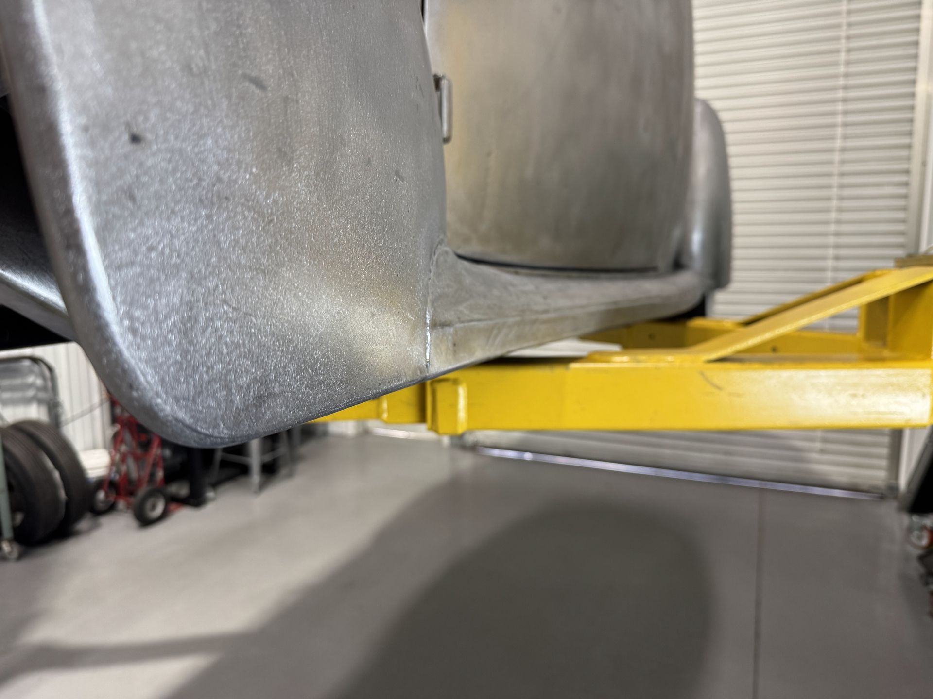 A trailer is sitting on top of a yellow ramp in a garage.