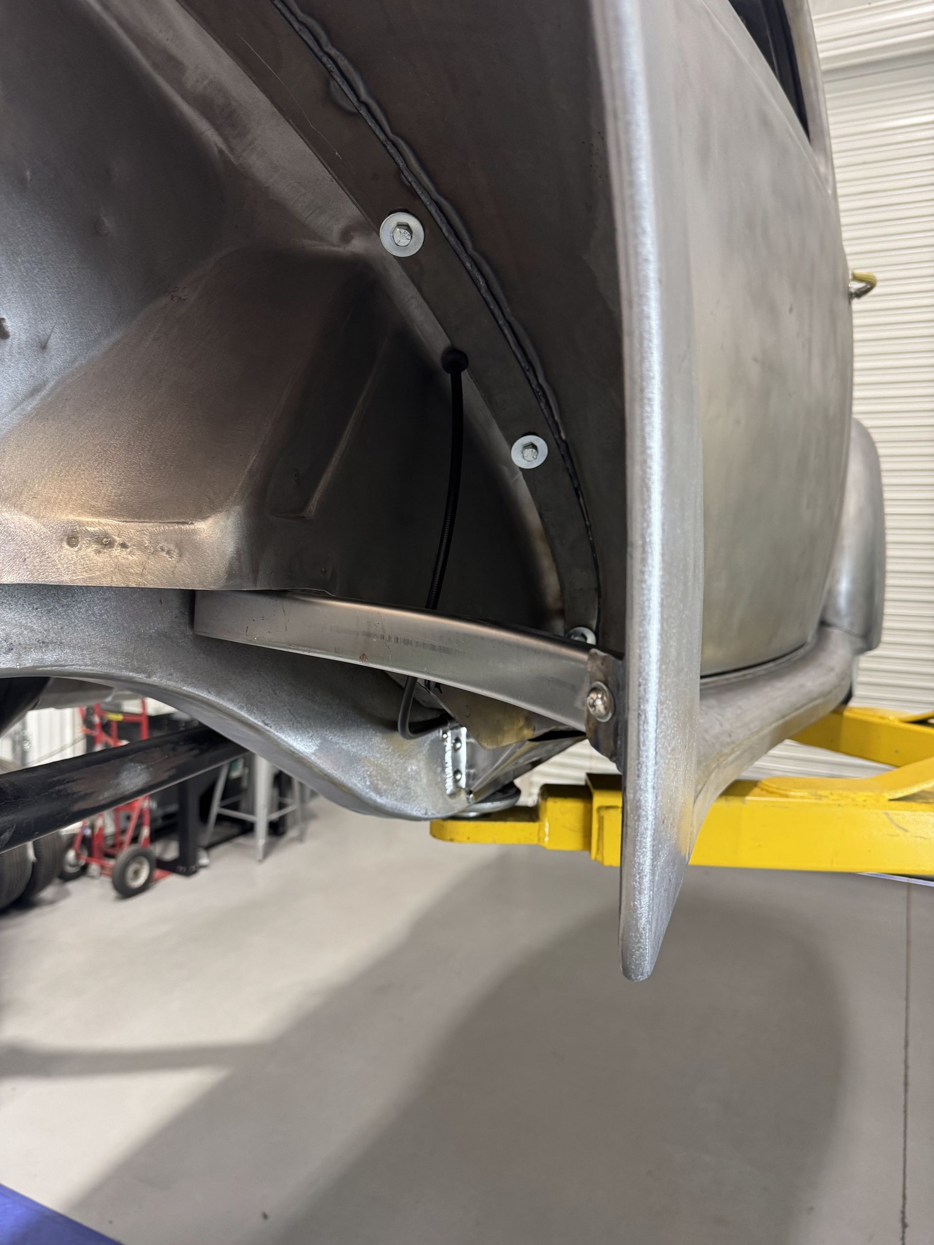 A car is sitting on a yellow lift in a garage.