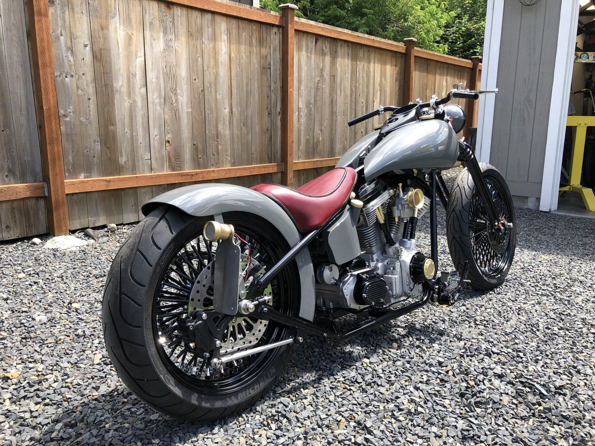 A motorcycle is parked in front of a wooden fence.