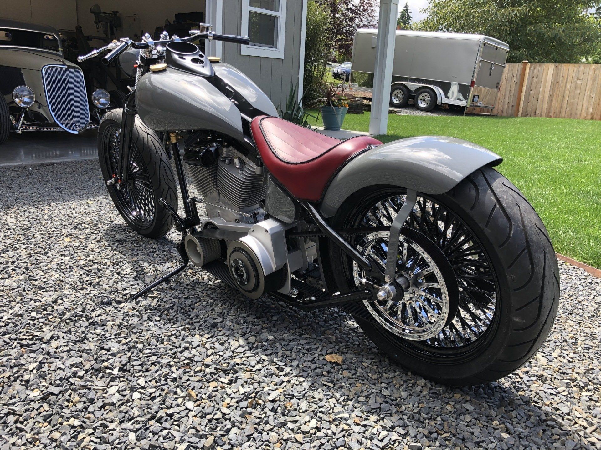 A motorcycle is parked on gravel in front of a garage.