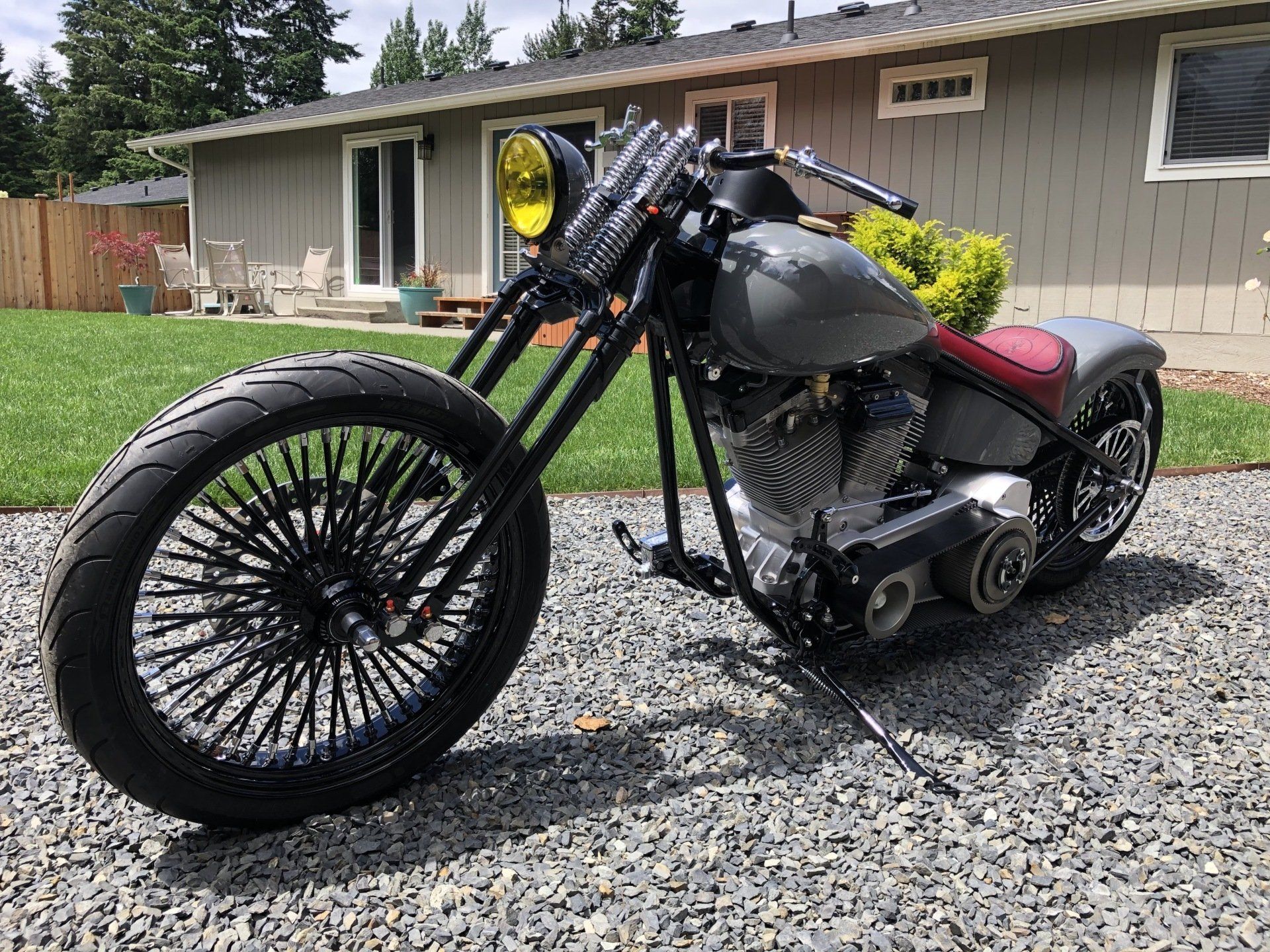 A motorcycle is parked in front of a house on gravel.