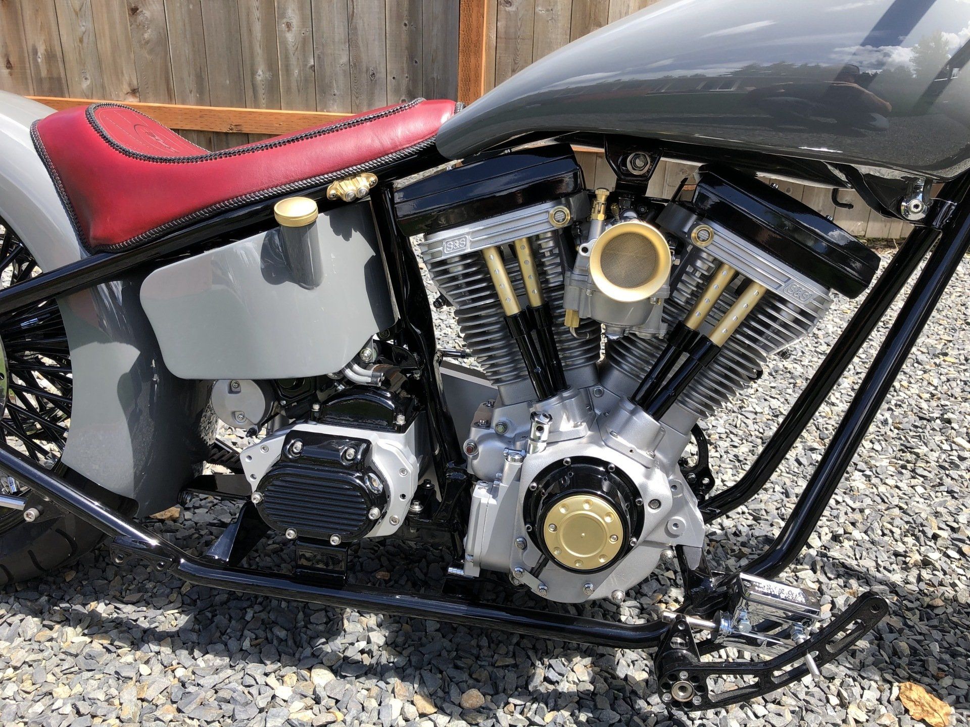 A close up of a motorcycle engine on a gravel road.