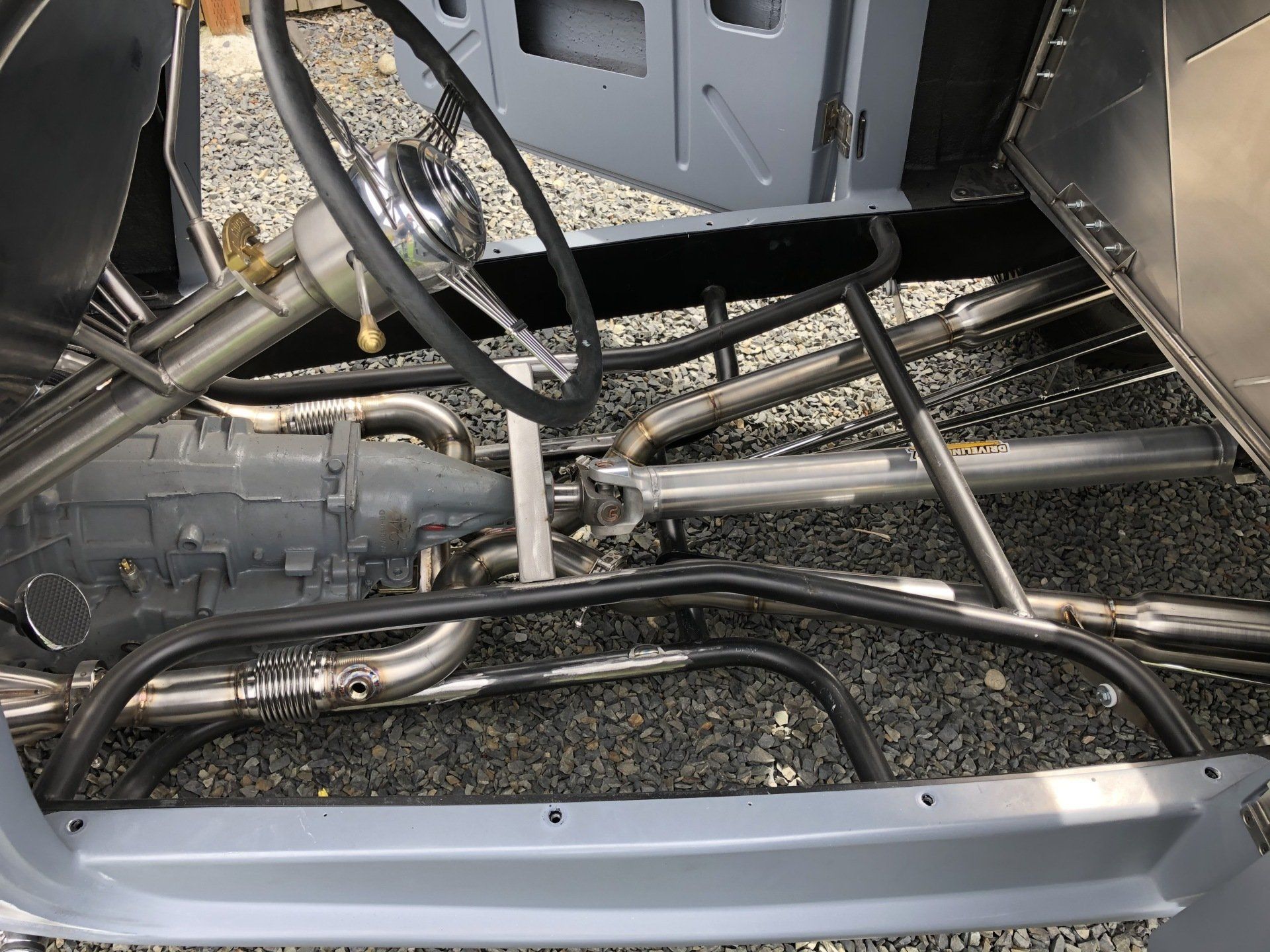 A close up of the inside of a car with a steering wheel and exhaust pipes.