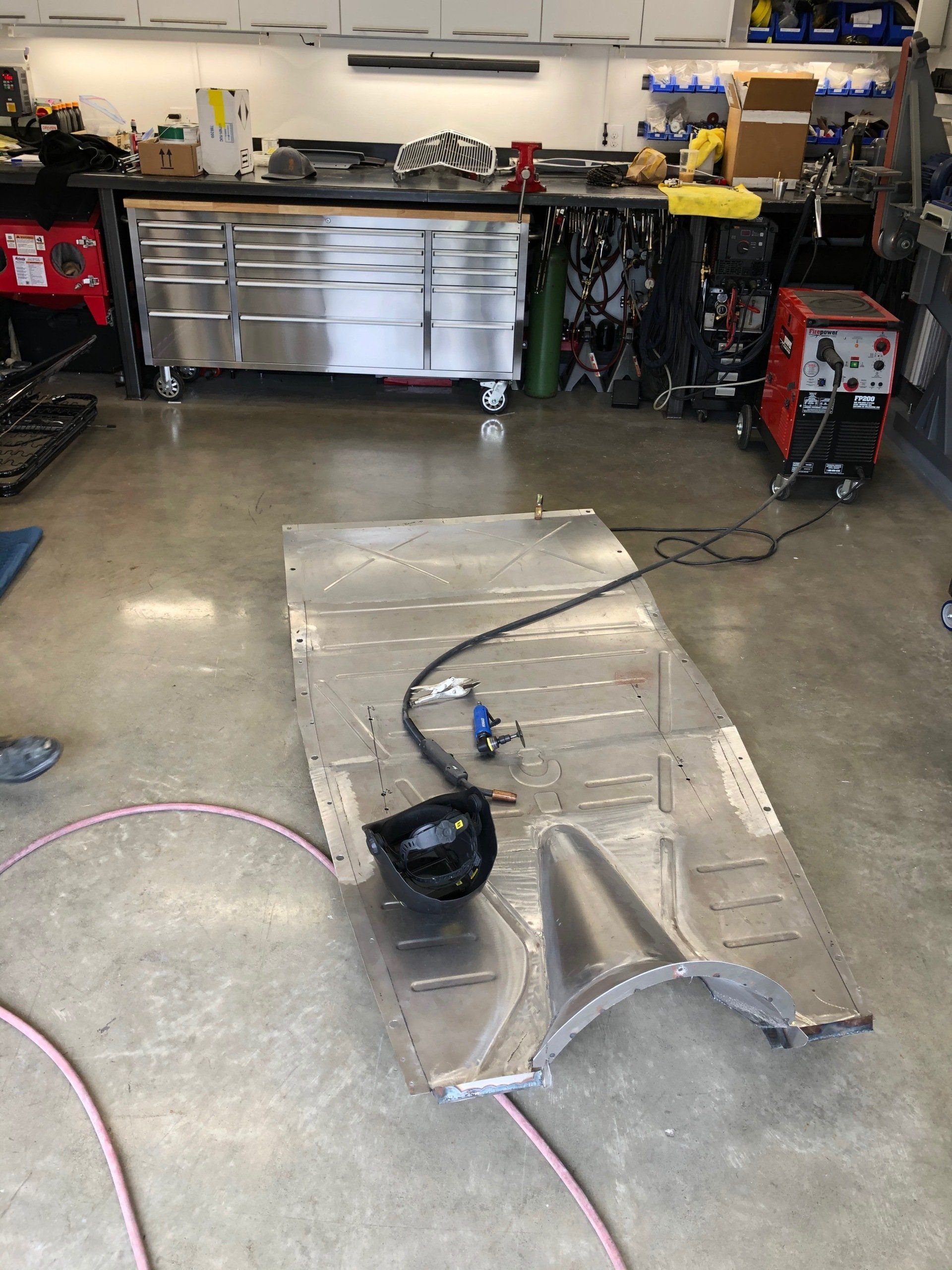 A large piece of metal is laying on the floor in a garage.