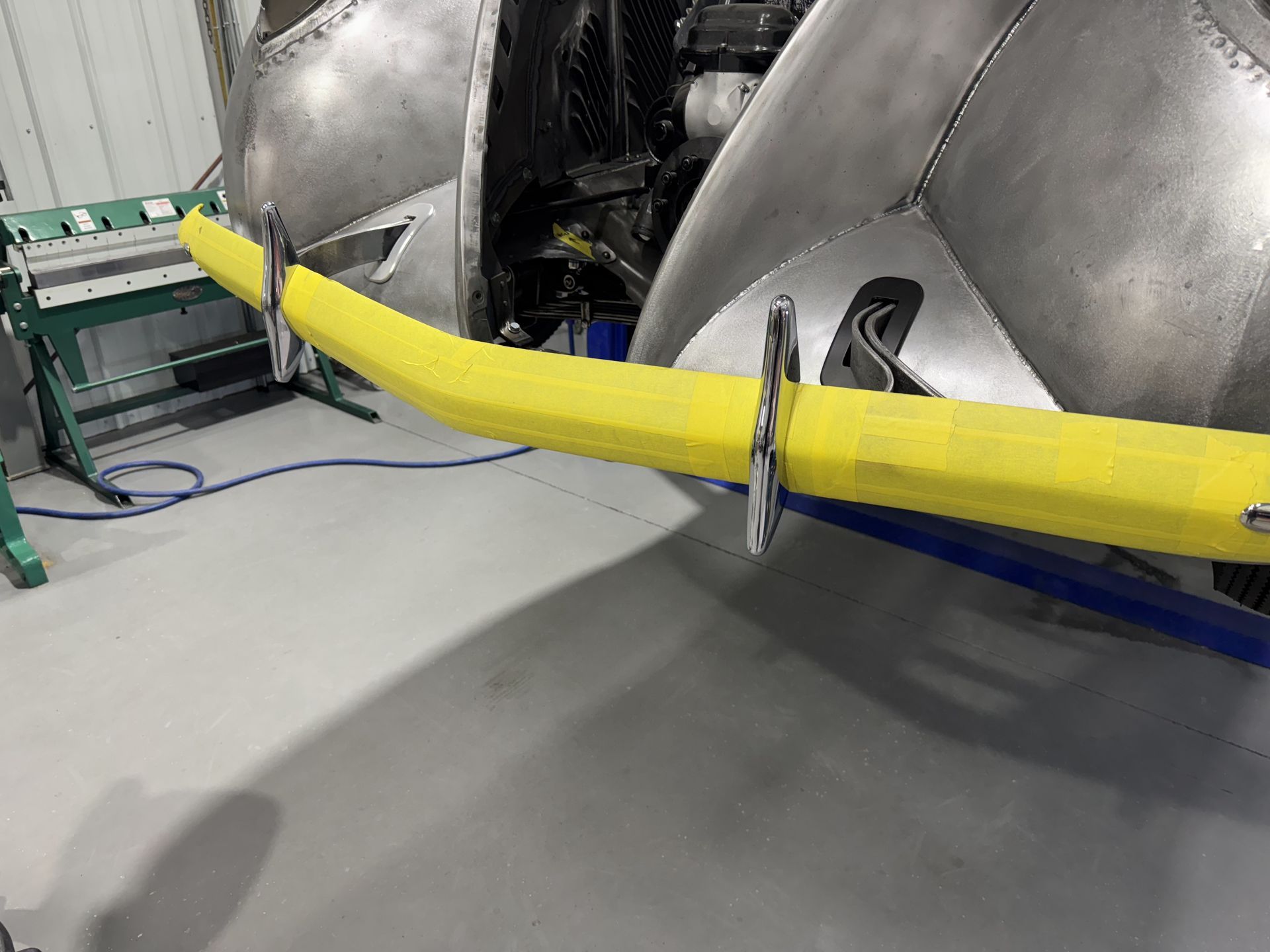 A yellow hose is attached to a metal object in a garage.
