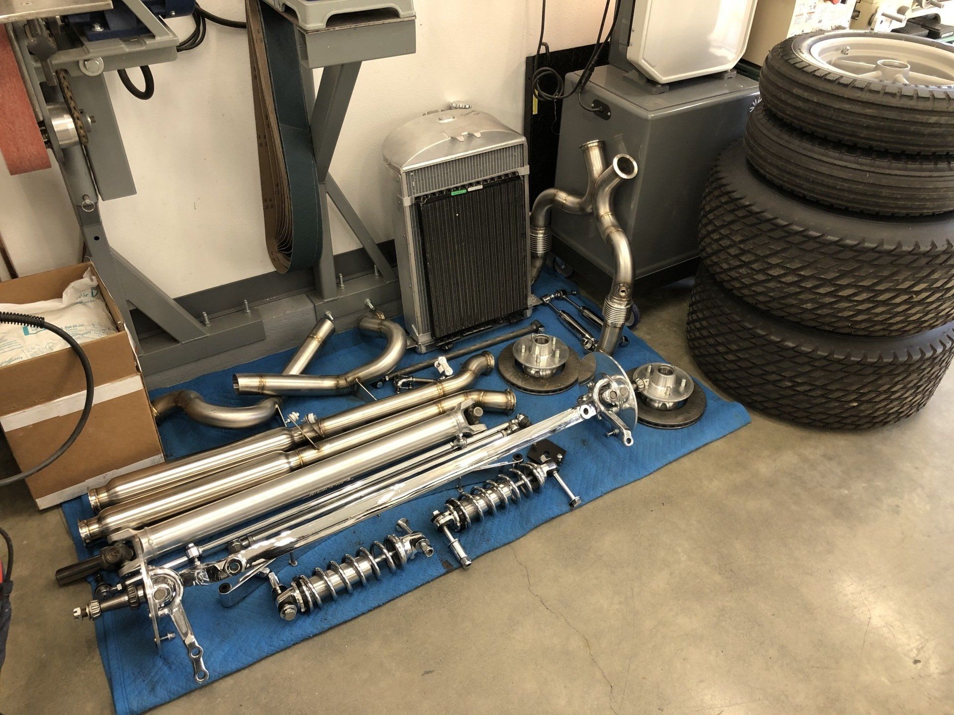A bunch of parts are sitting on a blue mat in a garage.