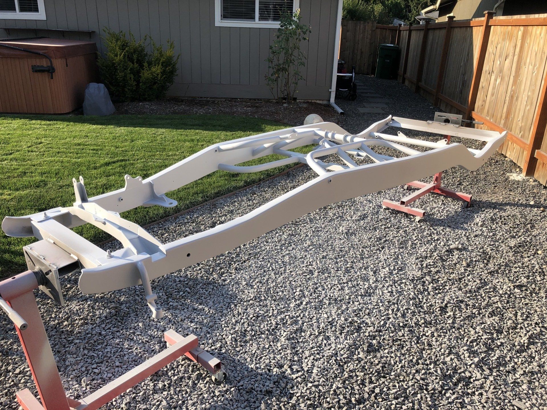 A white metal frame is sitting on gravel in front of a house.