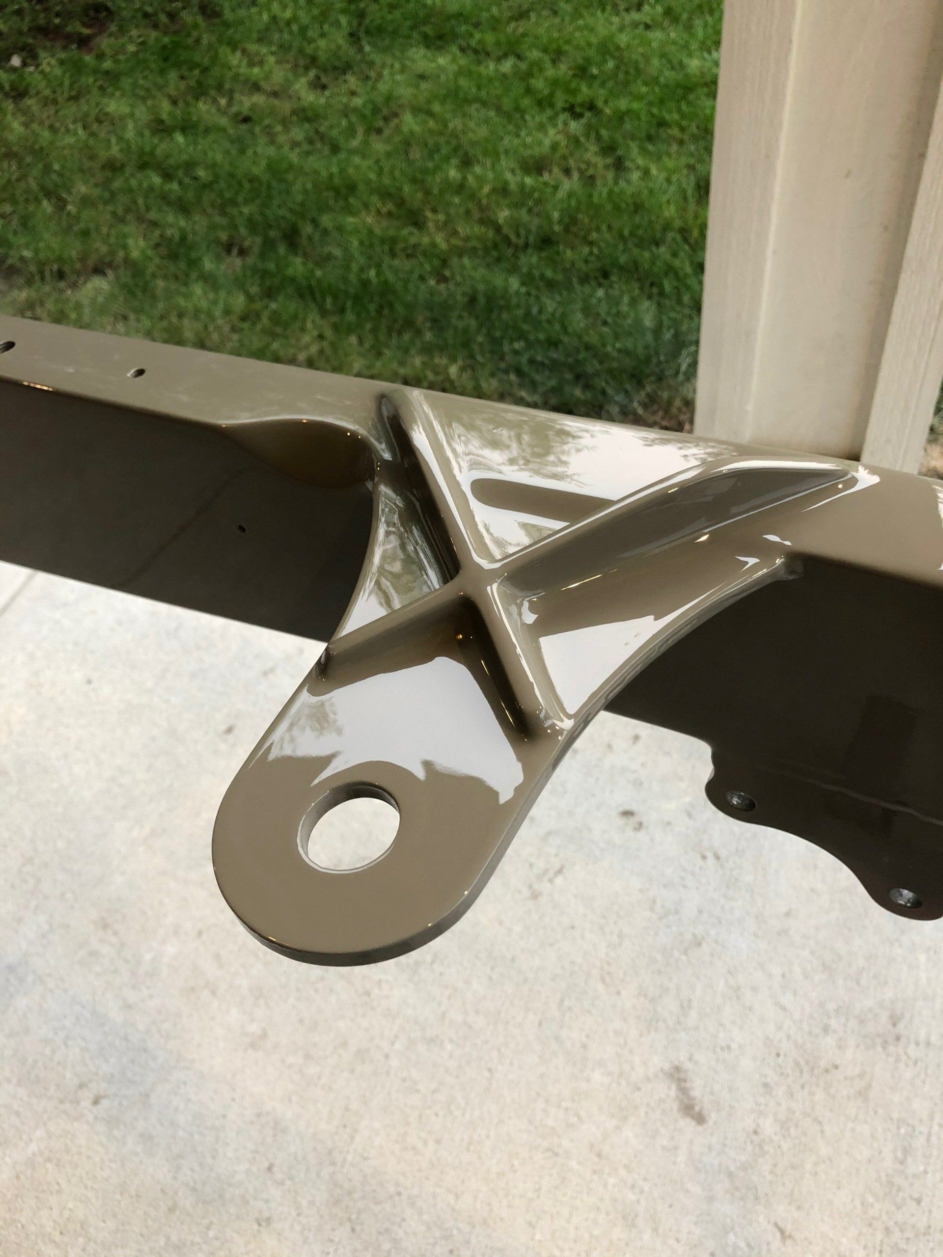 A piece of metal with a hole in it is sitting on a concrete surface.