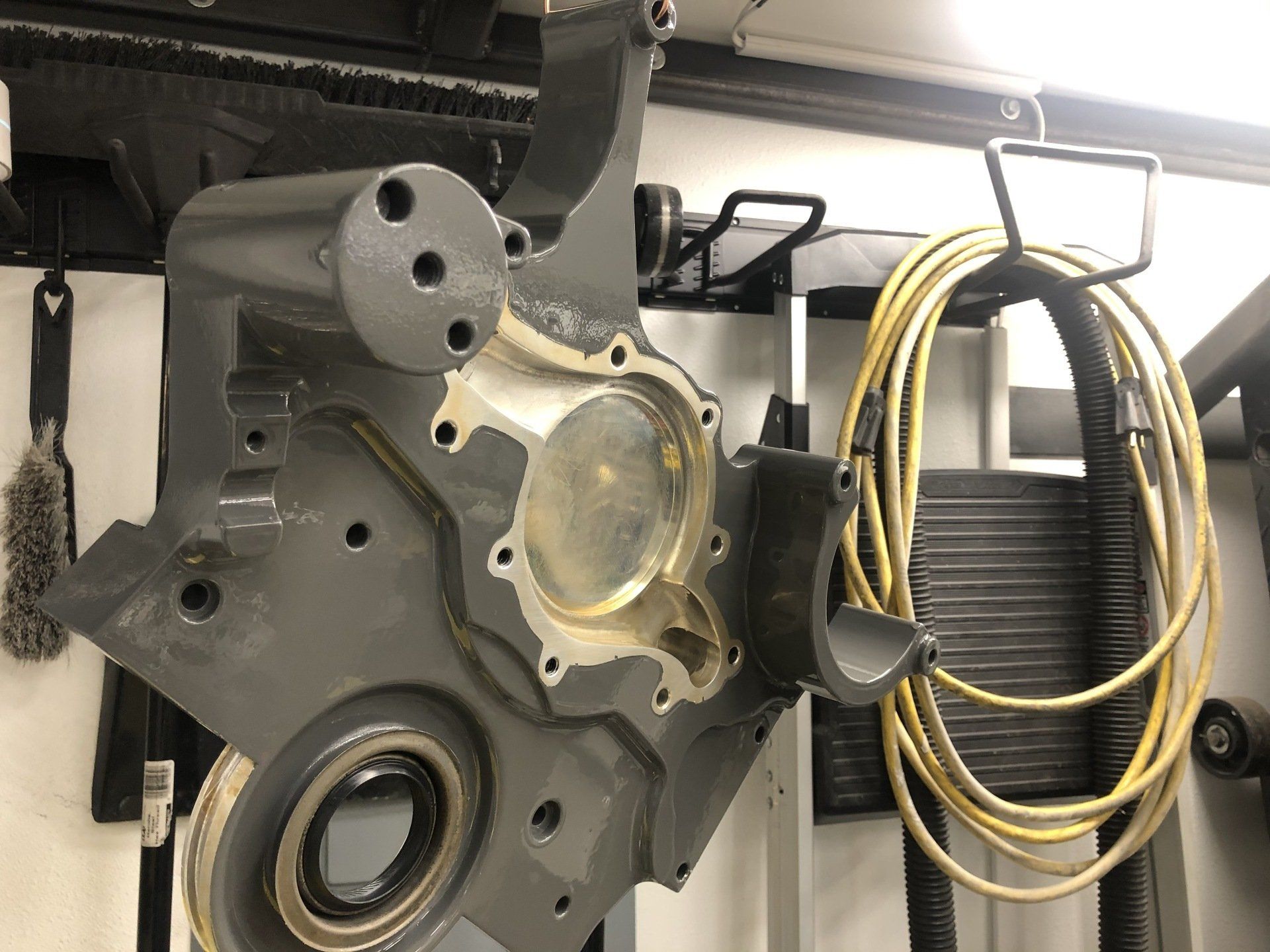 A piece of metal is hanging on a wall next to a yellow cord.