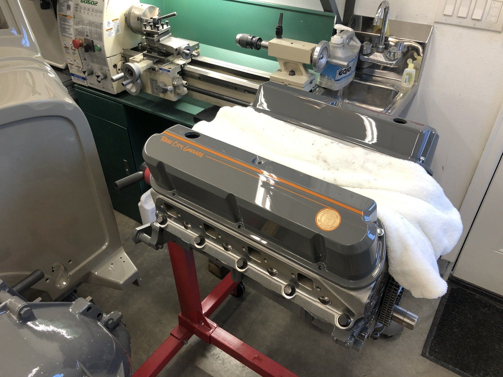 A motor is sitting on a stand next to a lathe.