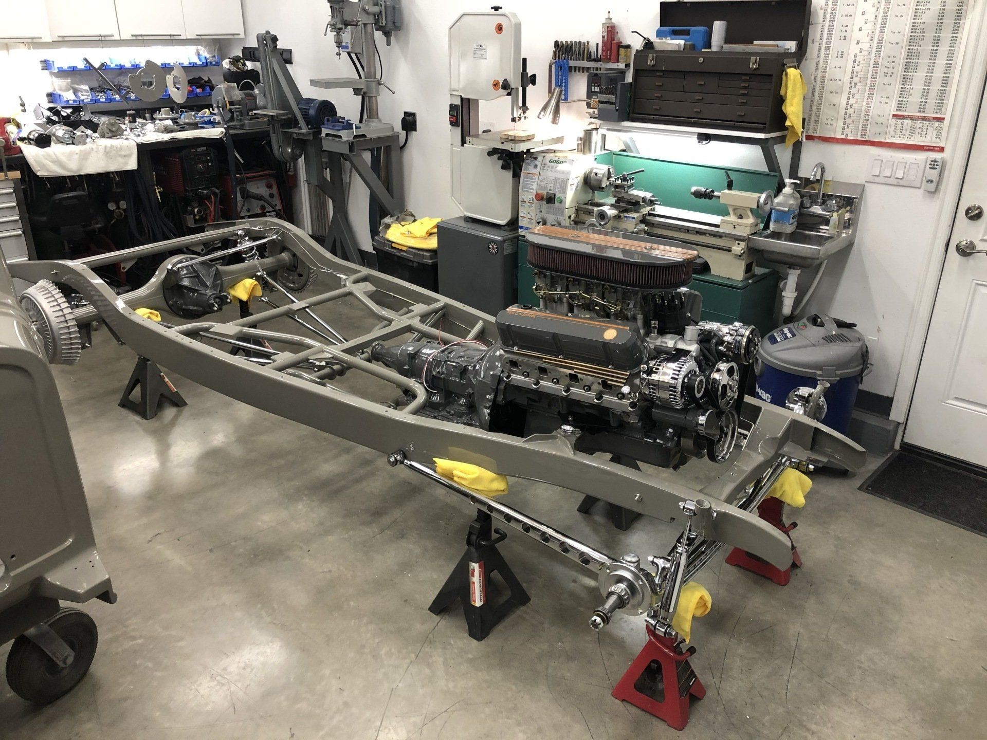 A car chassis is sitting on a table in a garage.