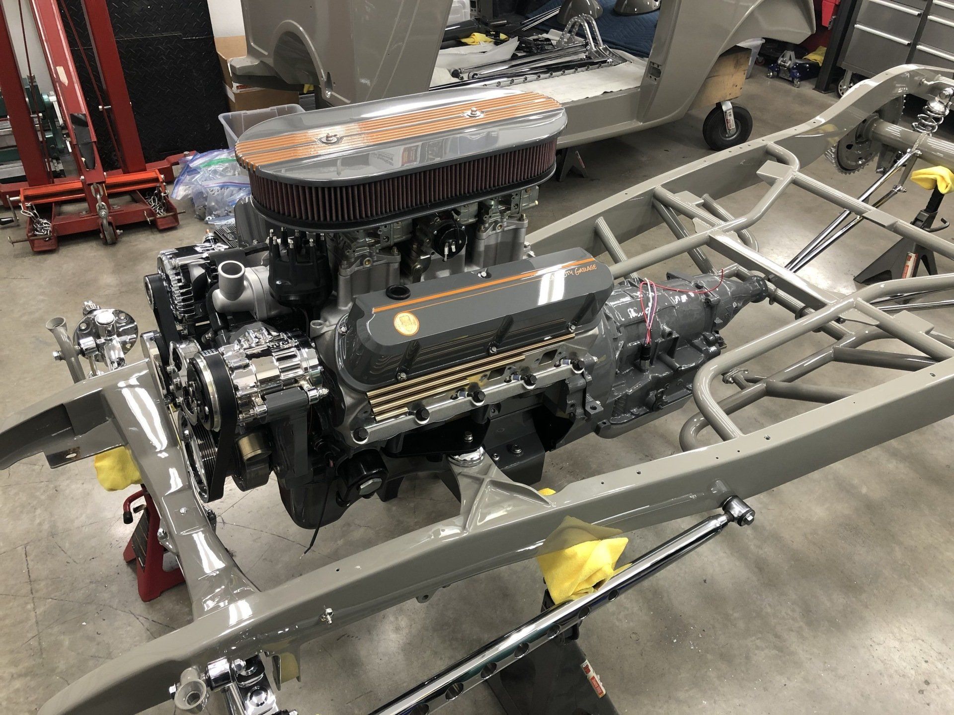 A car engine is sitting on top of a chassis in a garage.