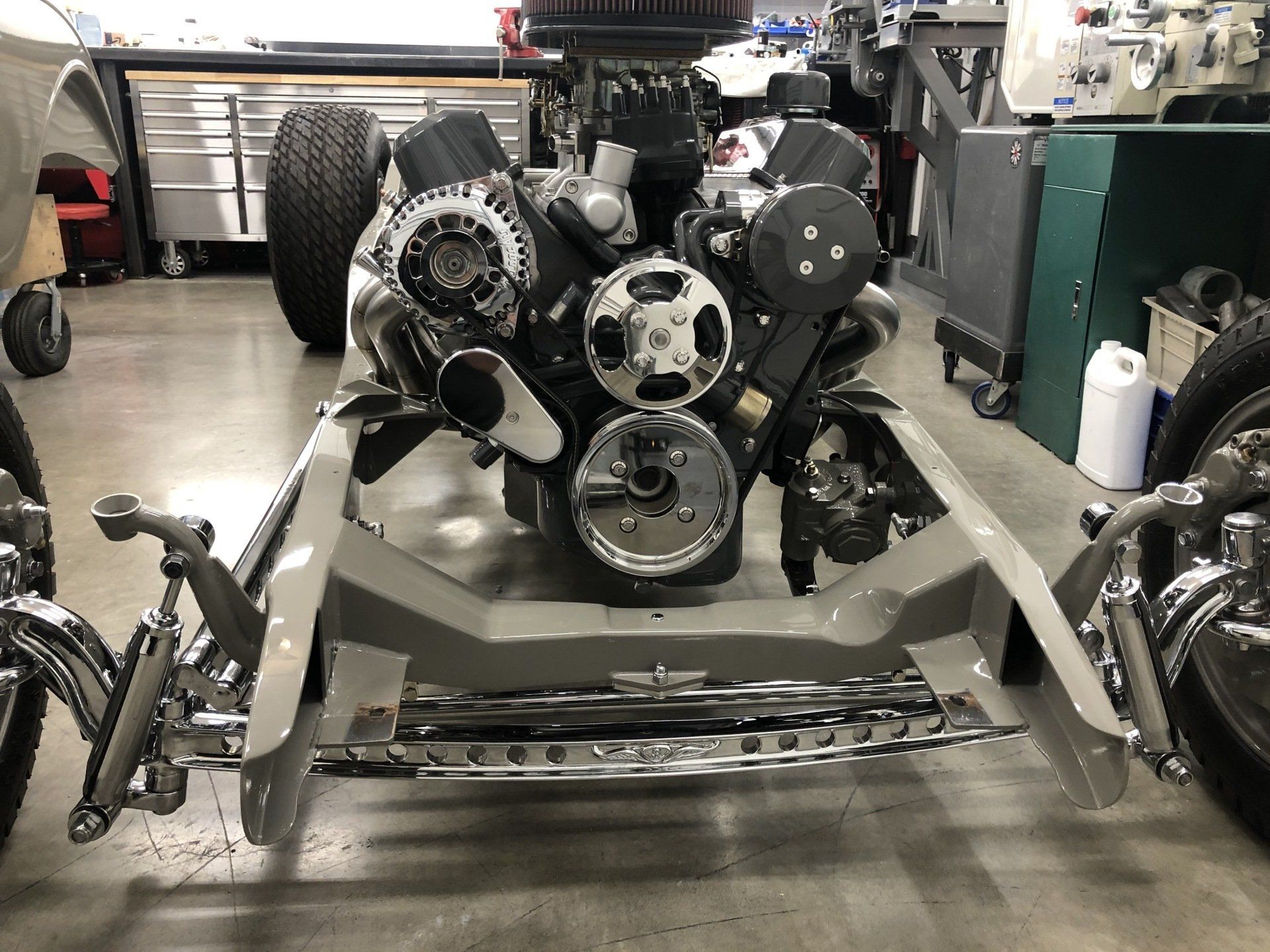 A motorcycle engine is sitting on a concrete floor in a garage.