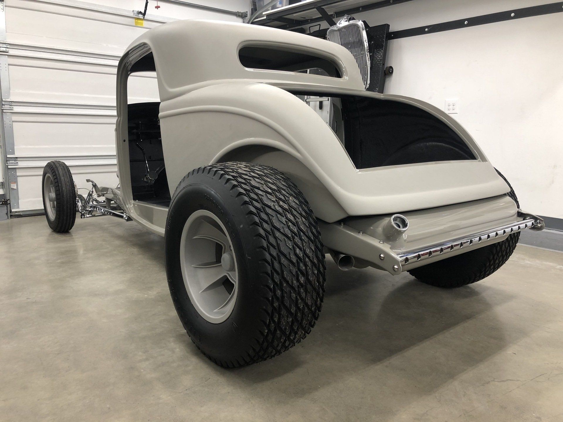 A white car is parked in a garage next to a garage door.