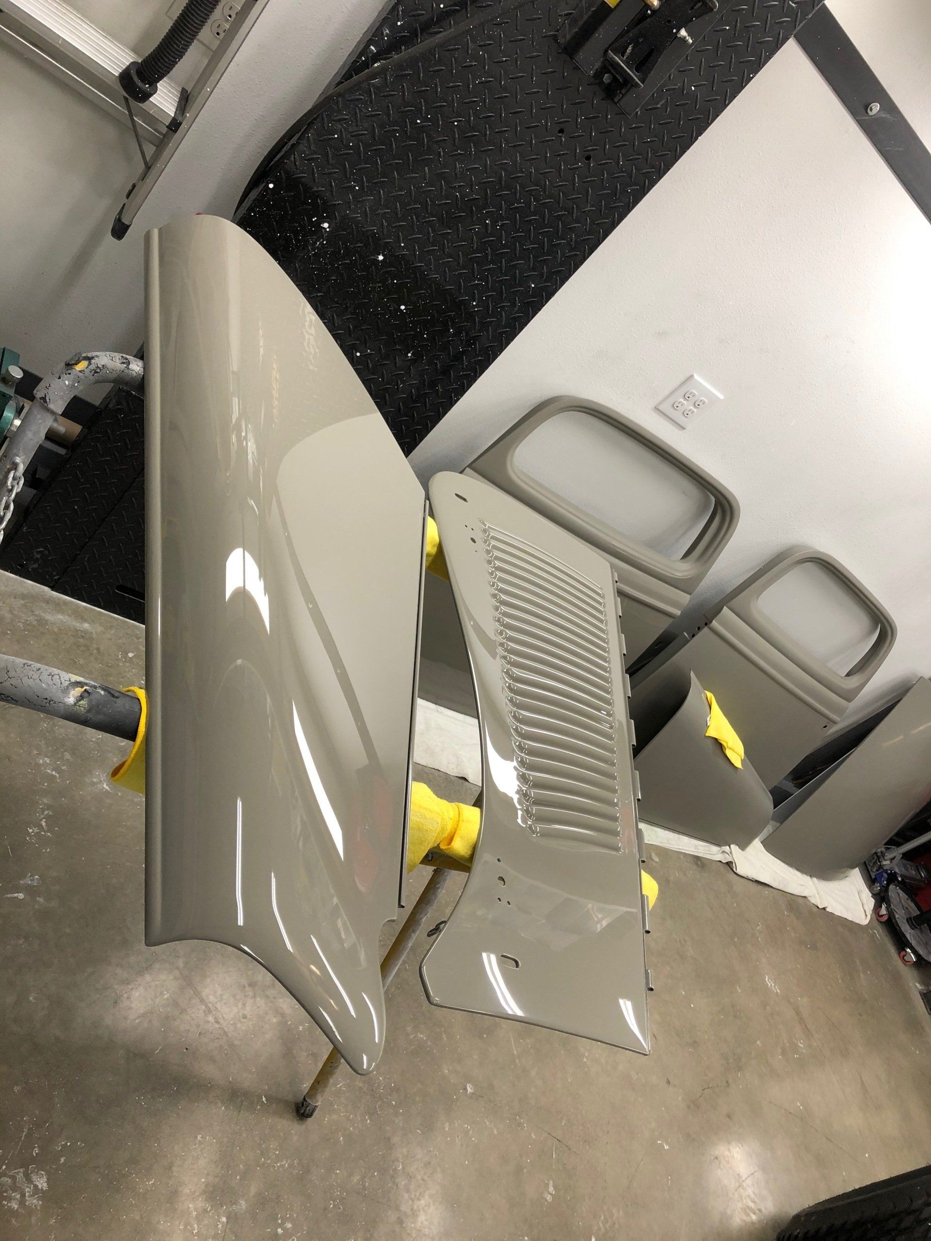 A car hood is sitting on top of a concrete floor in a garage.