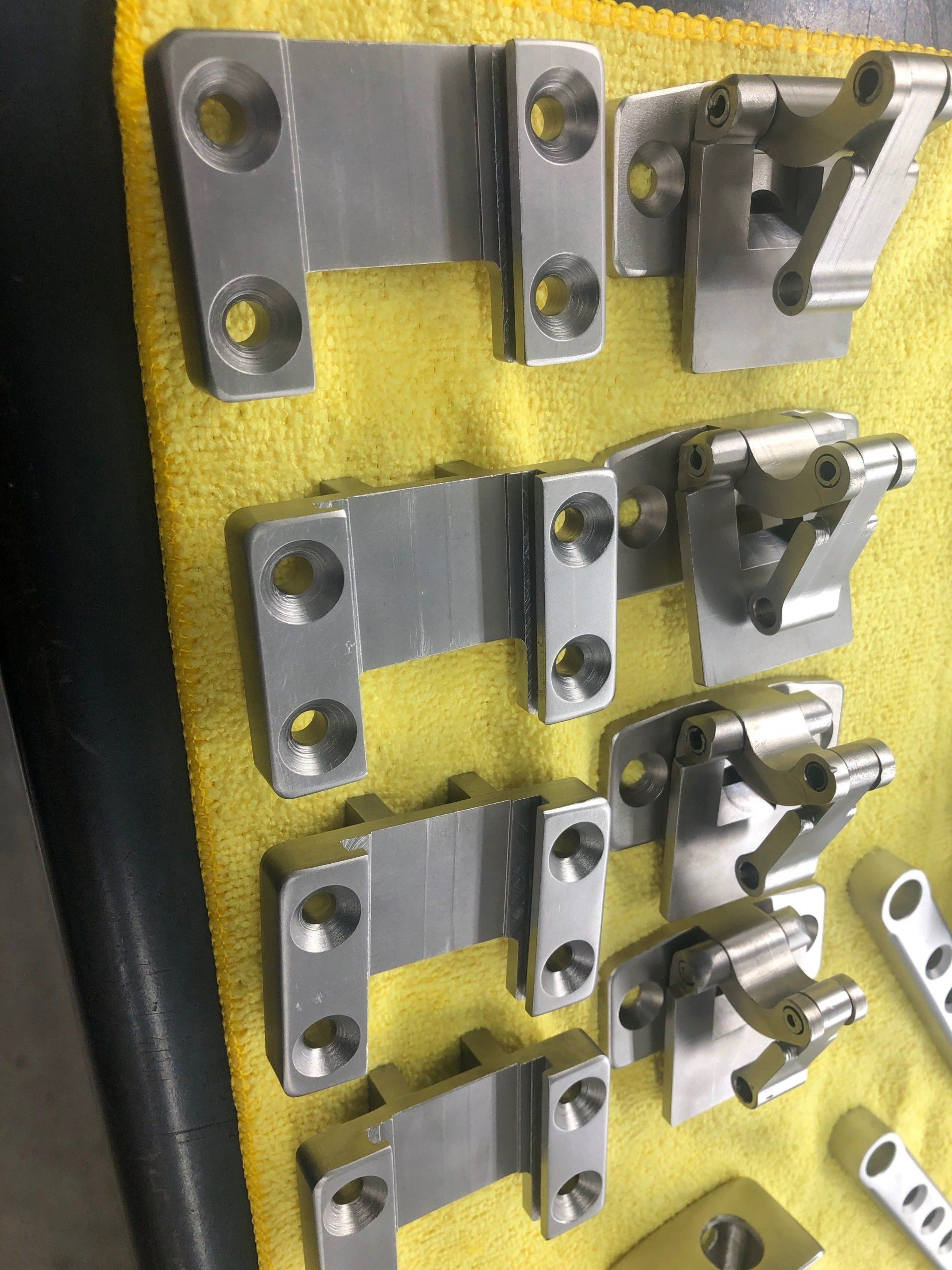 A bunch of metal parts are laying on a yellow cloth