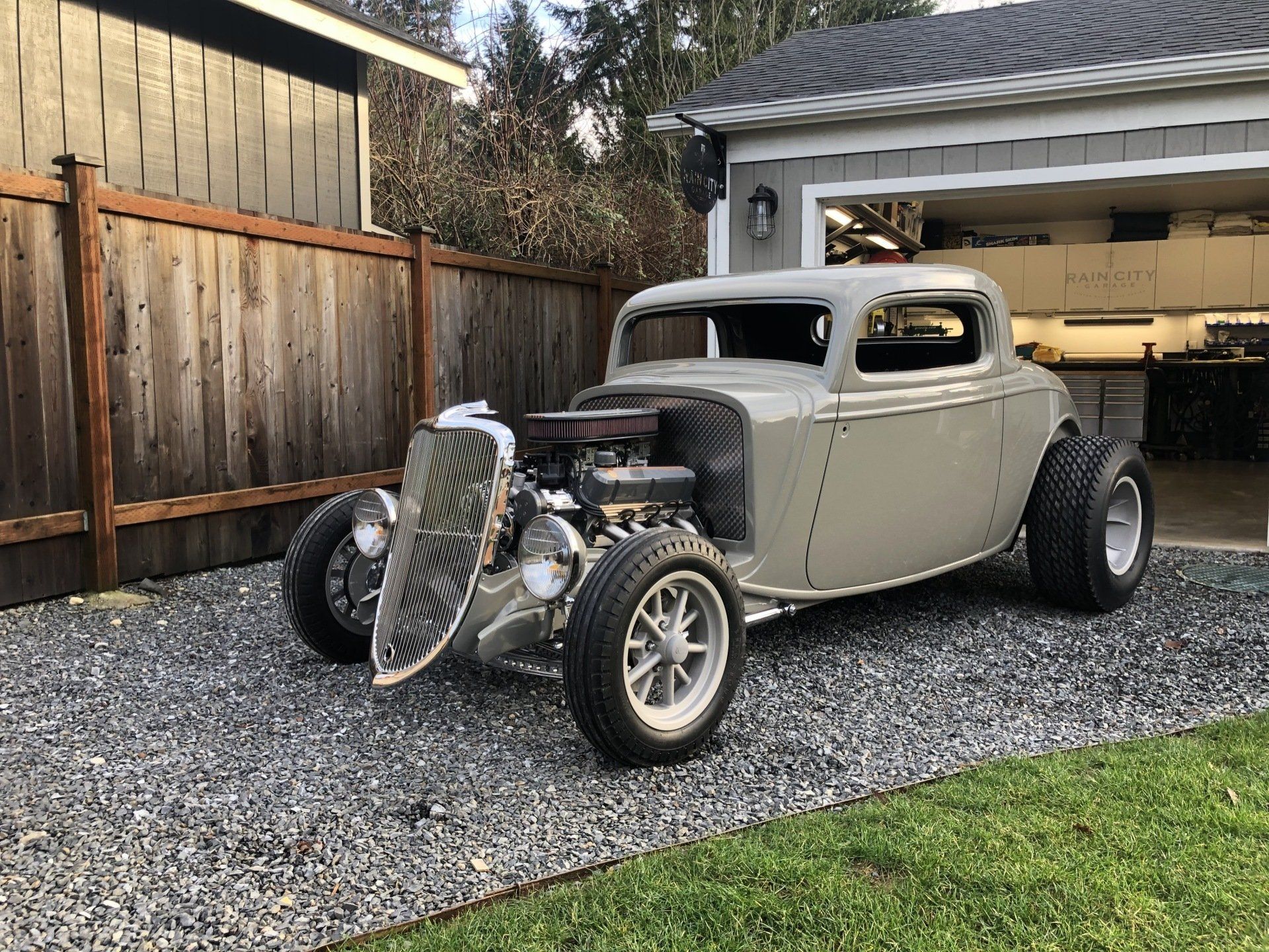 A hot rod is parked in front of a garage.