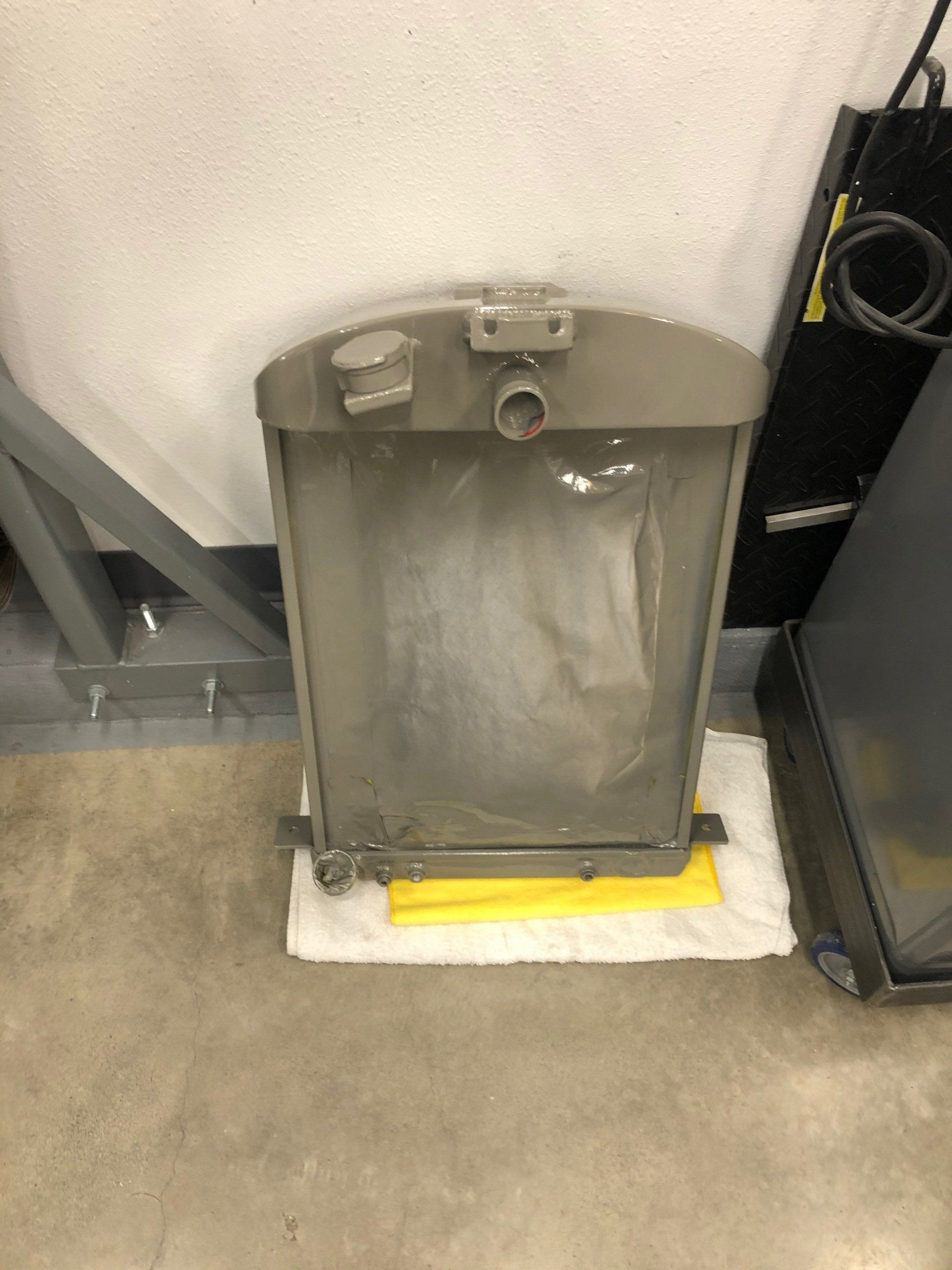 A stainless steel radiator is sitting on a towel on the floor.