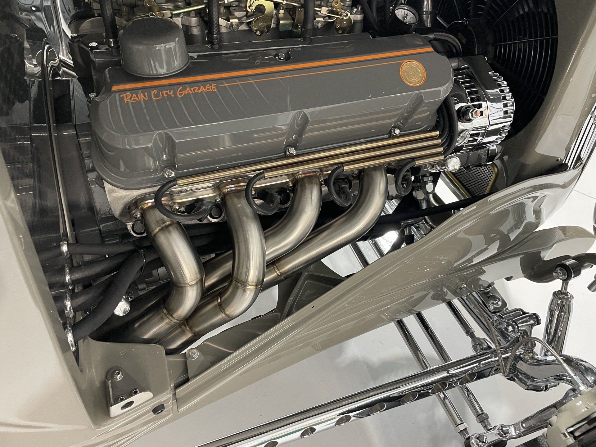 A close up of a car engine with a stainless steel exhaust pipe.