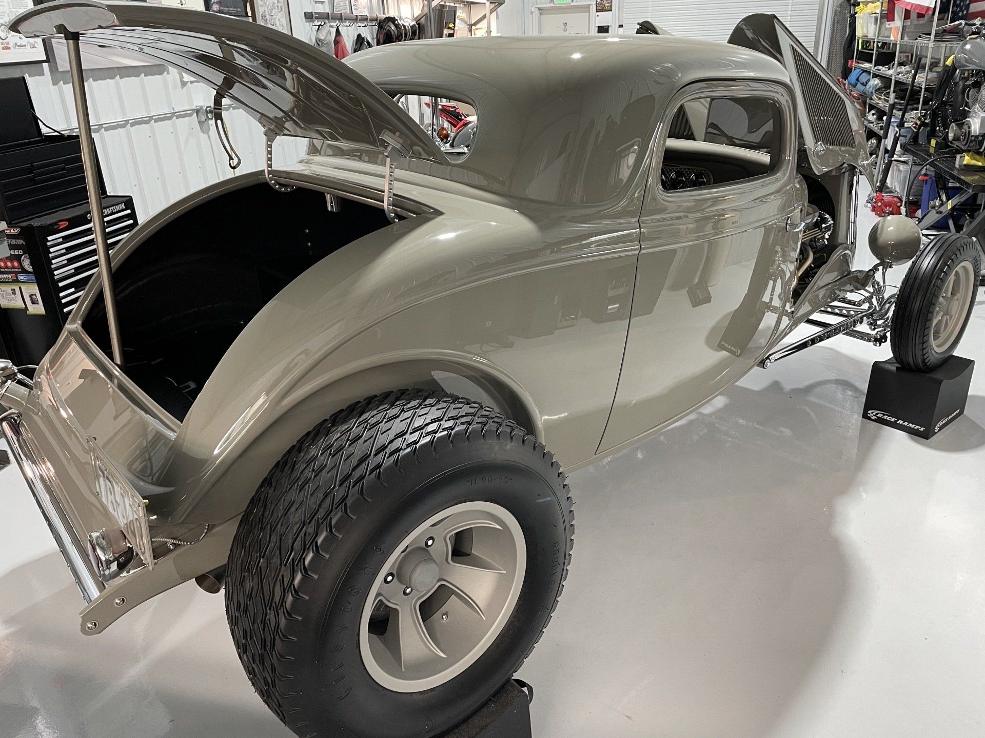 A car with the trunk open is on display in a garage