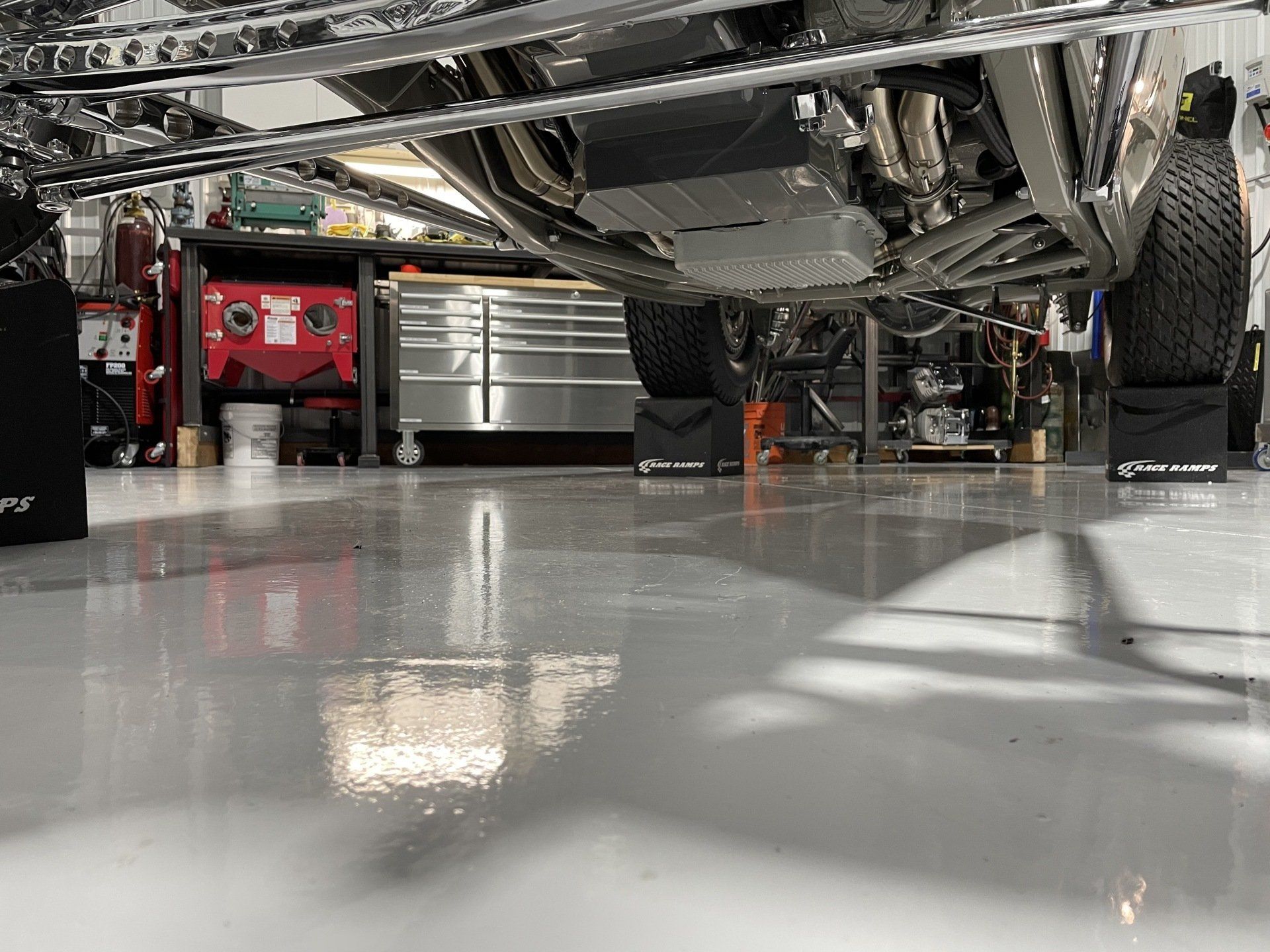 A car is parked in a garage with a white floor.