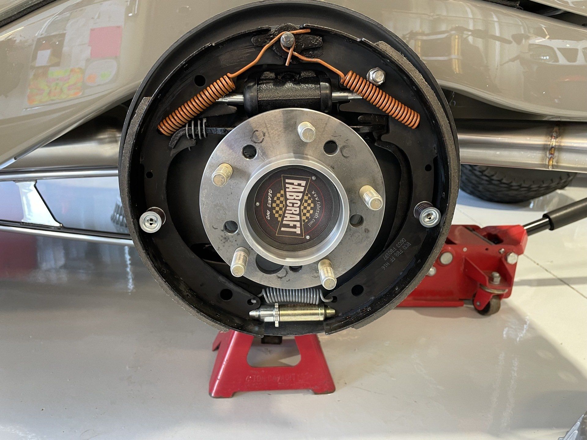 A close up of a car 's rear brake on a red jack.