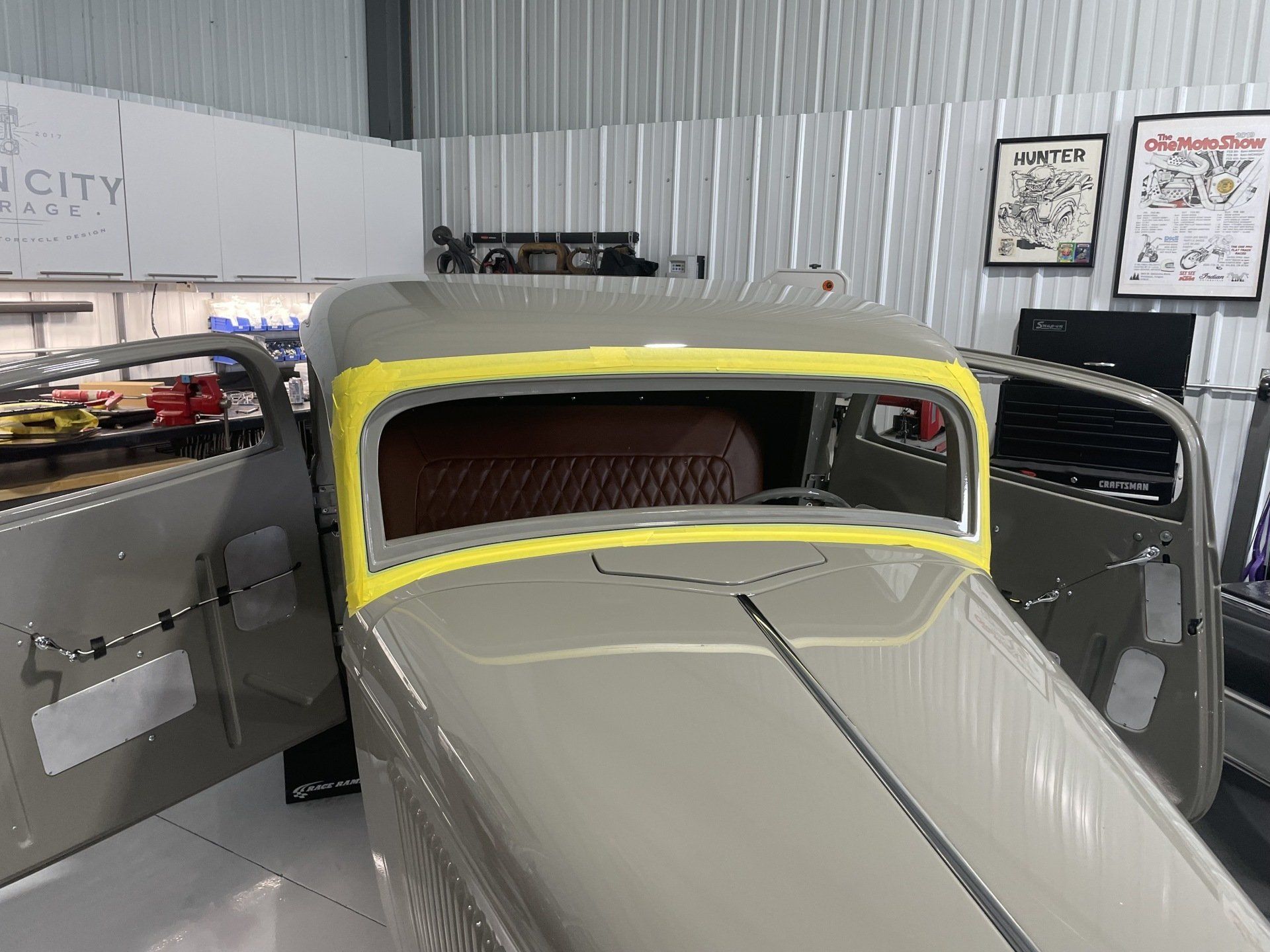 A car is sitting in a garage with a yellow tape around the windshield.