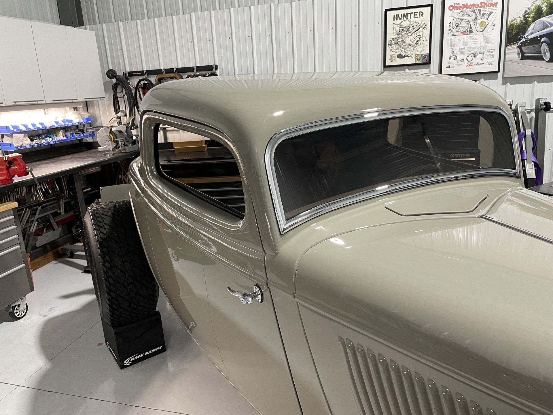A white car is parked in a garage next to a workbench.