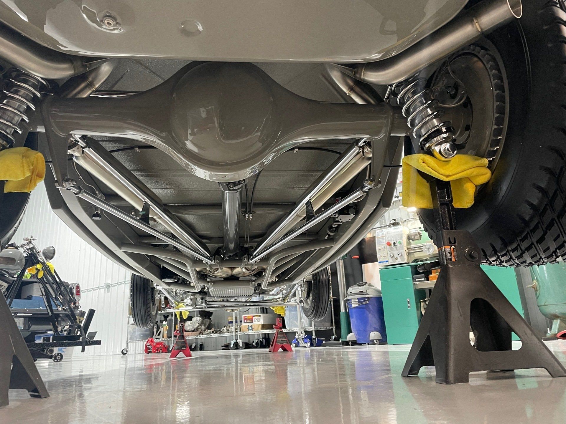 The underside of a car is being worked on in a garage.