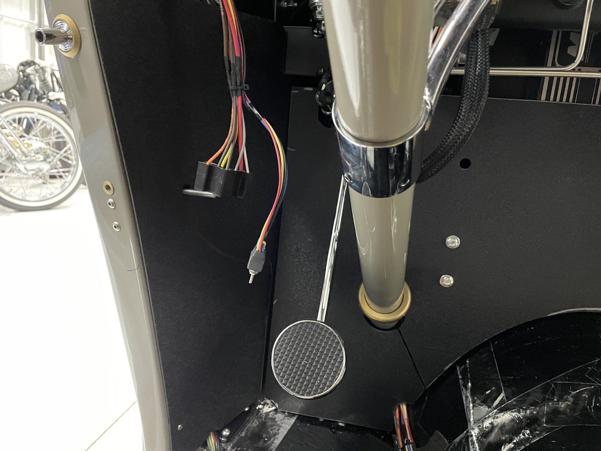 A close up of a pedal on a machine with a motorcycle in the background