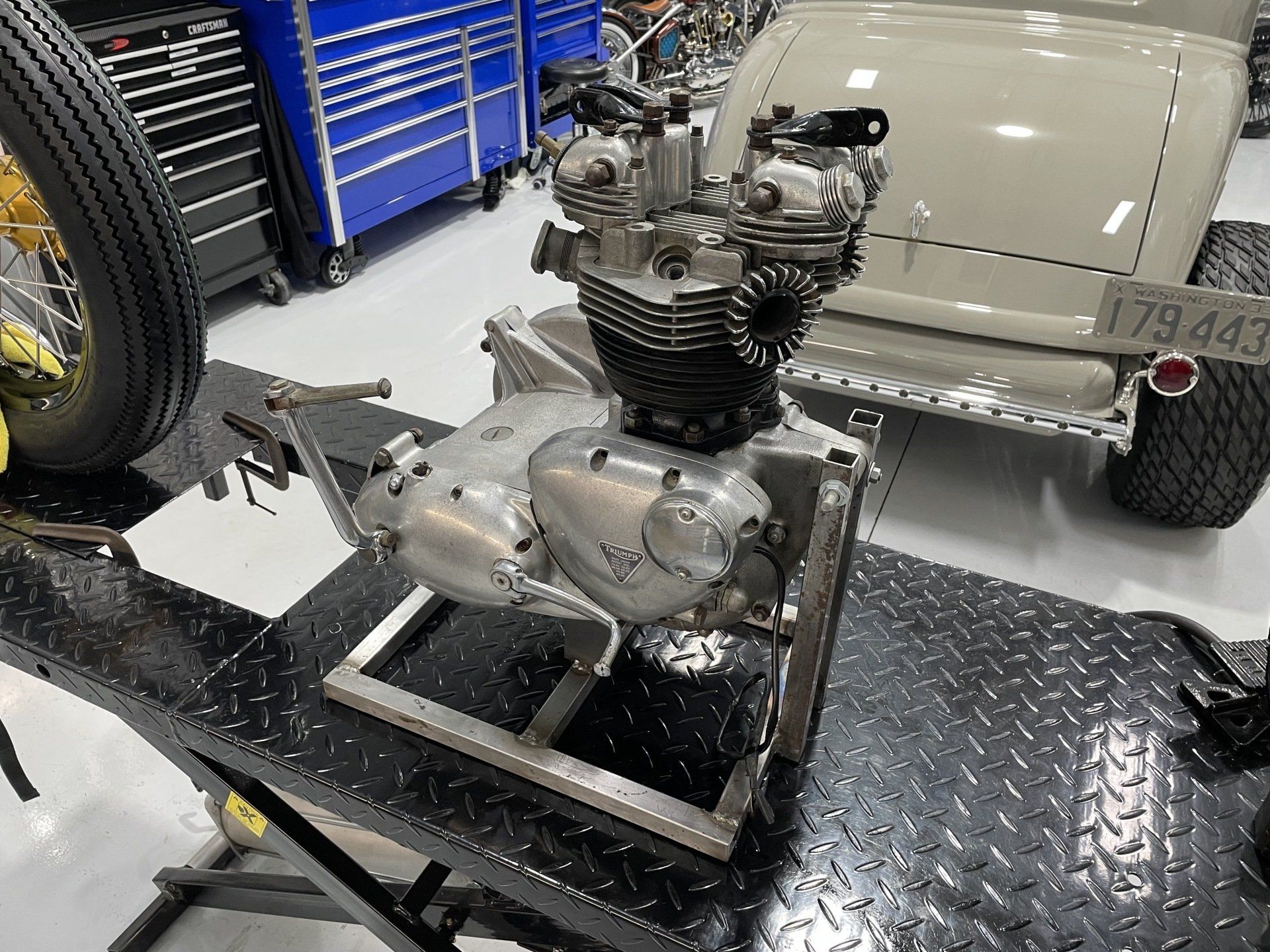 A motorcycle engine is sitting on a table in a garage.
