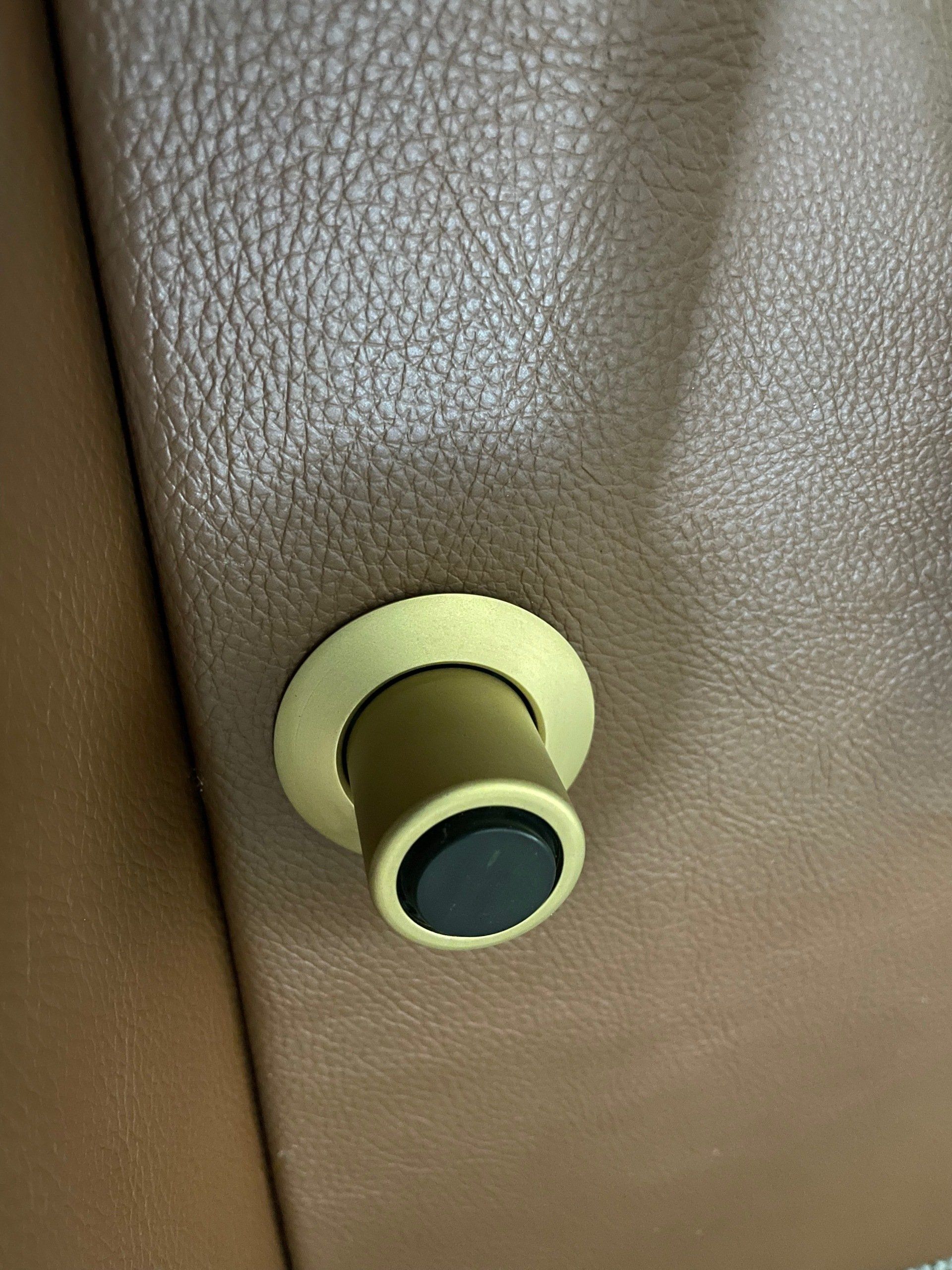 A close up of a door knob on a brown leather door.