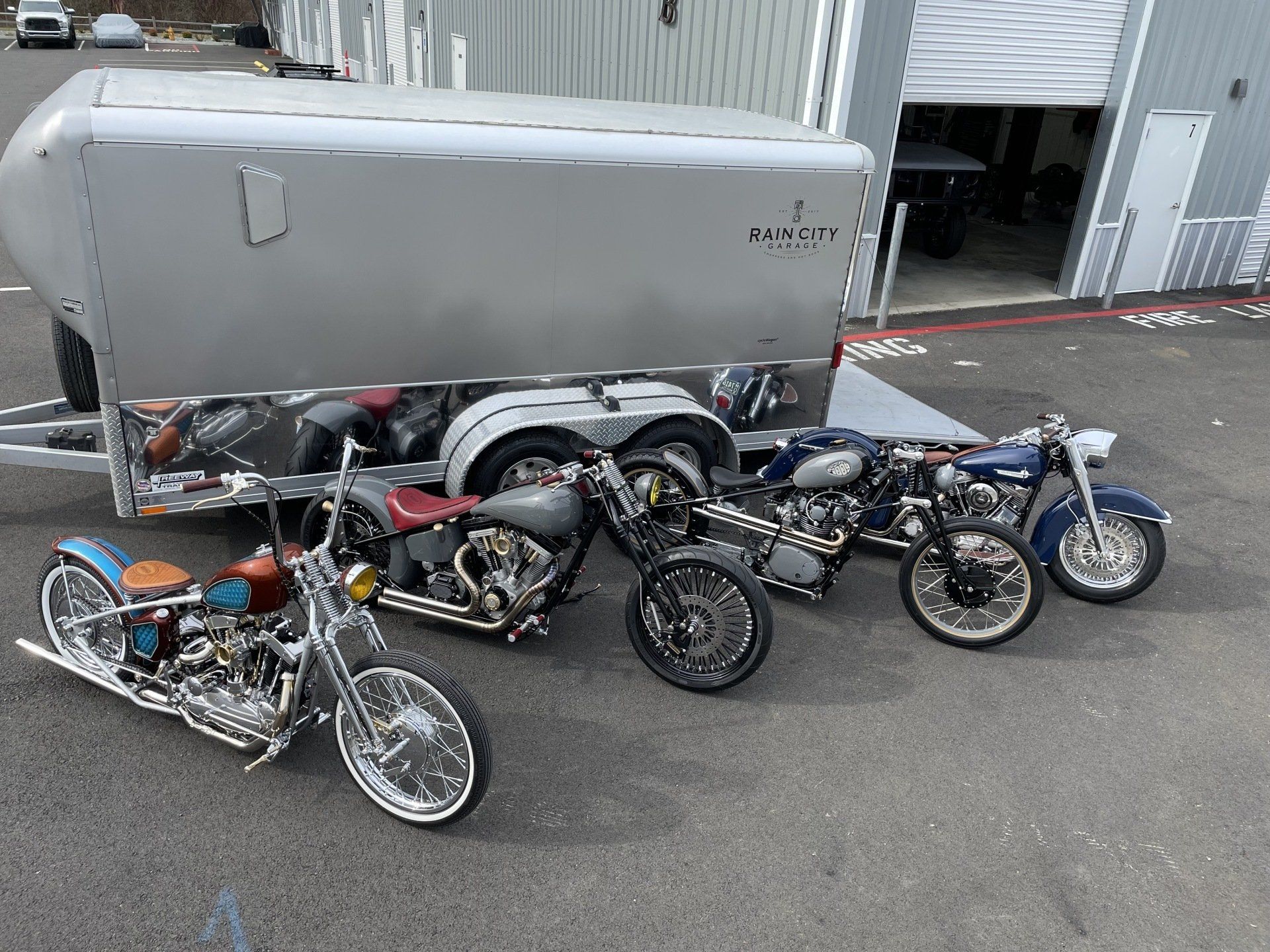 A group of motorcycles are parked in front of a trailer.