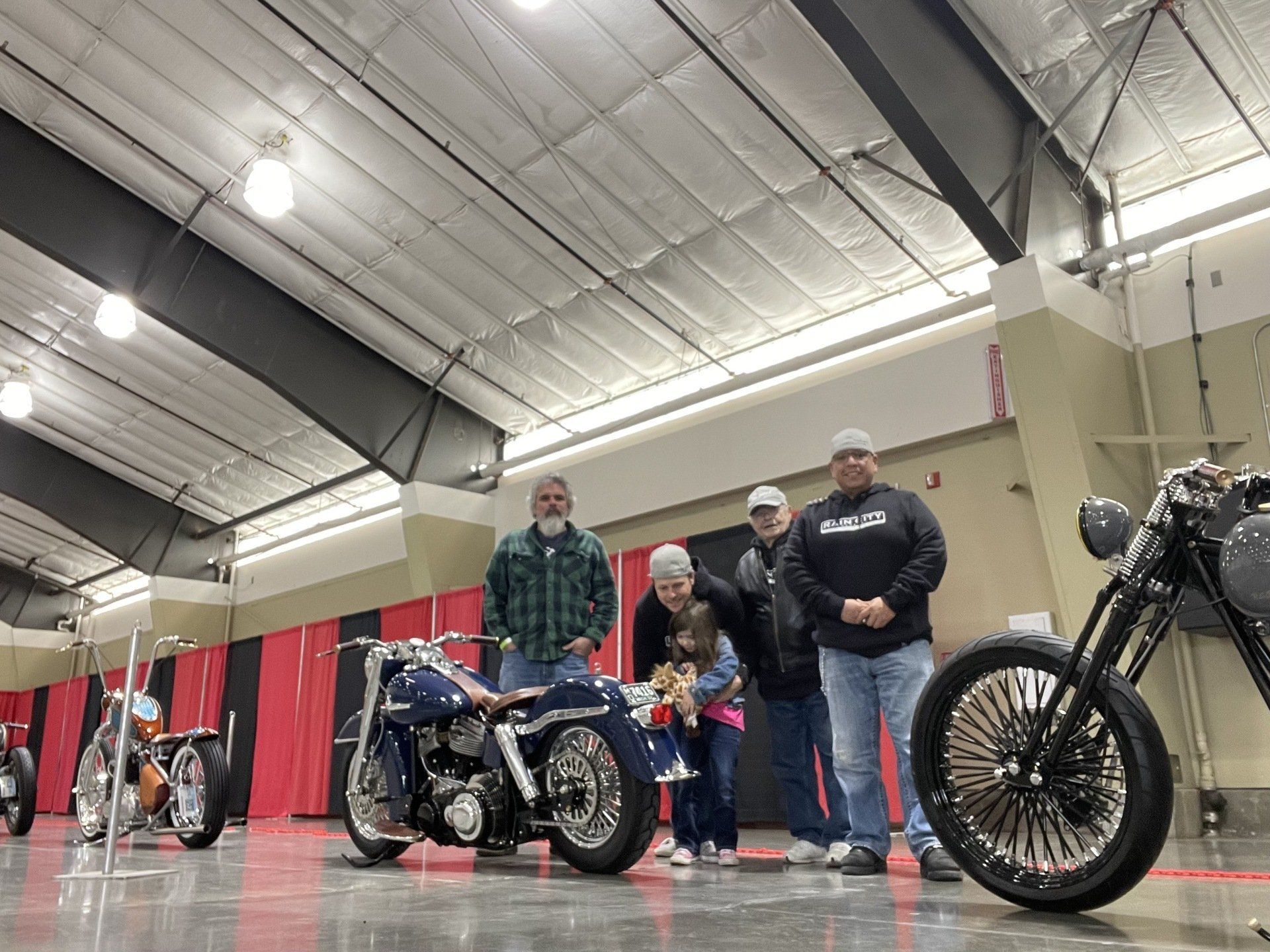 A group of people standing next to a motorcycle in a garage.