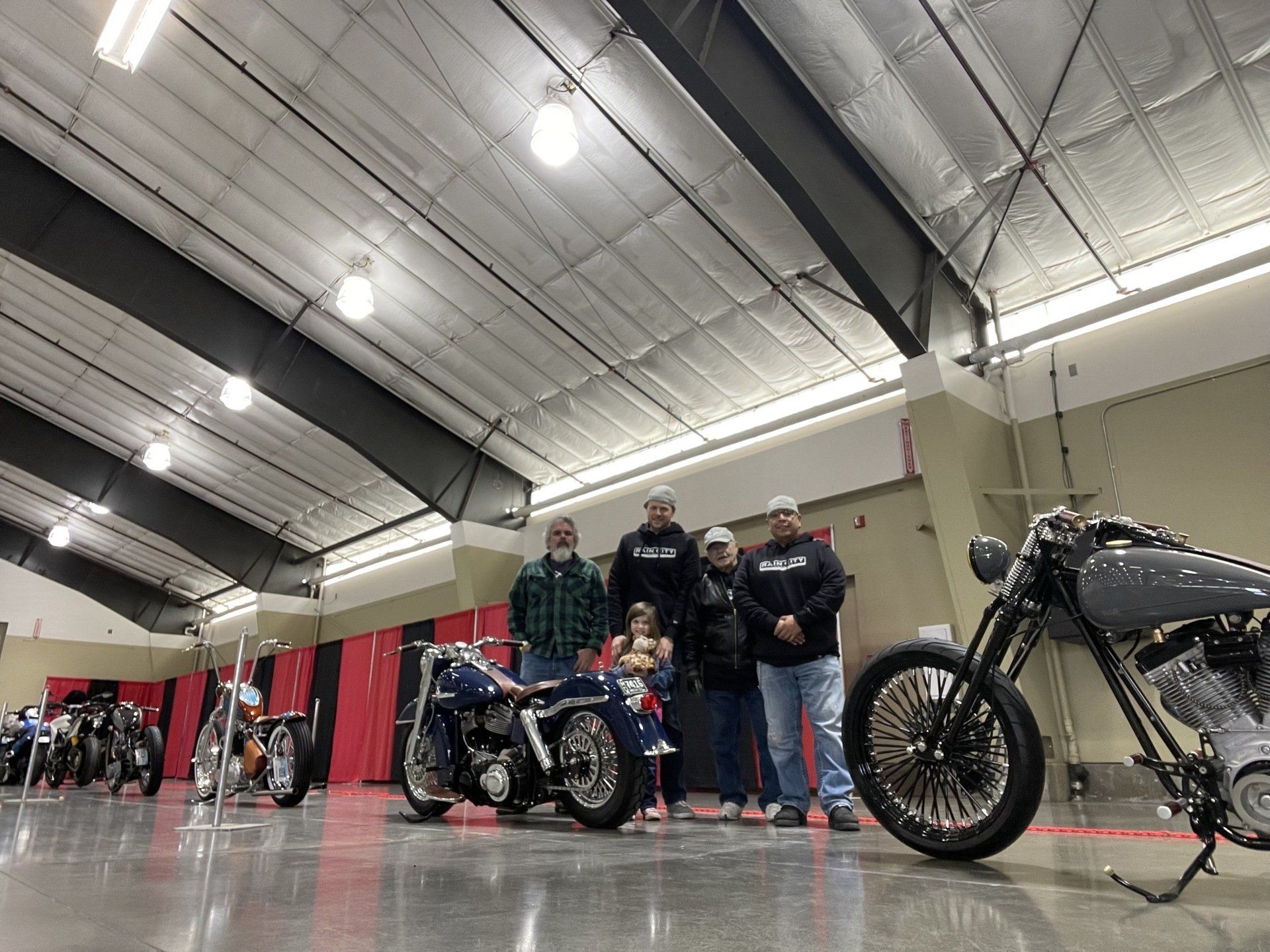 A group of people standing next to a motorcycle in a garage.