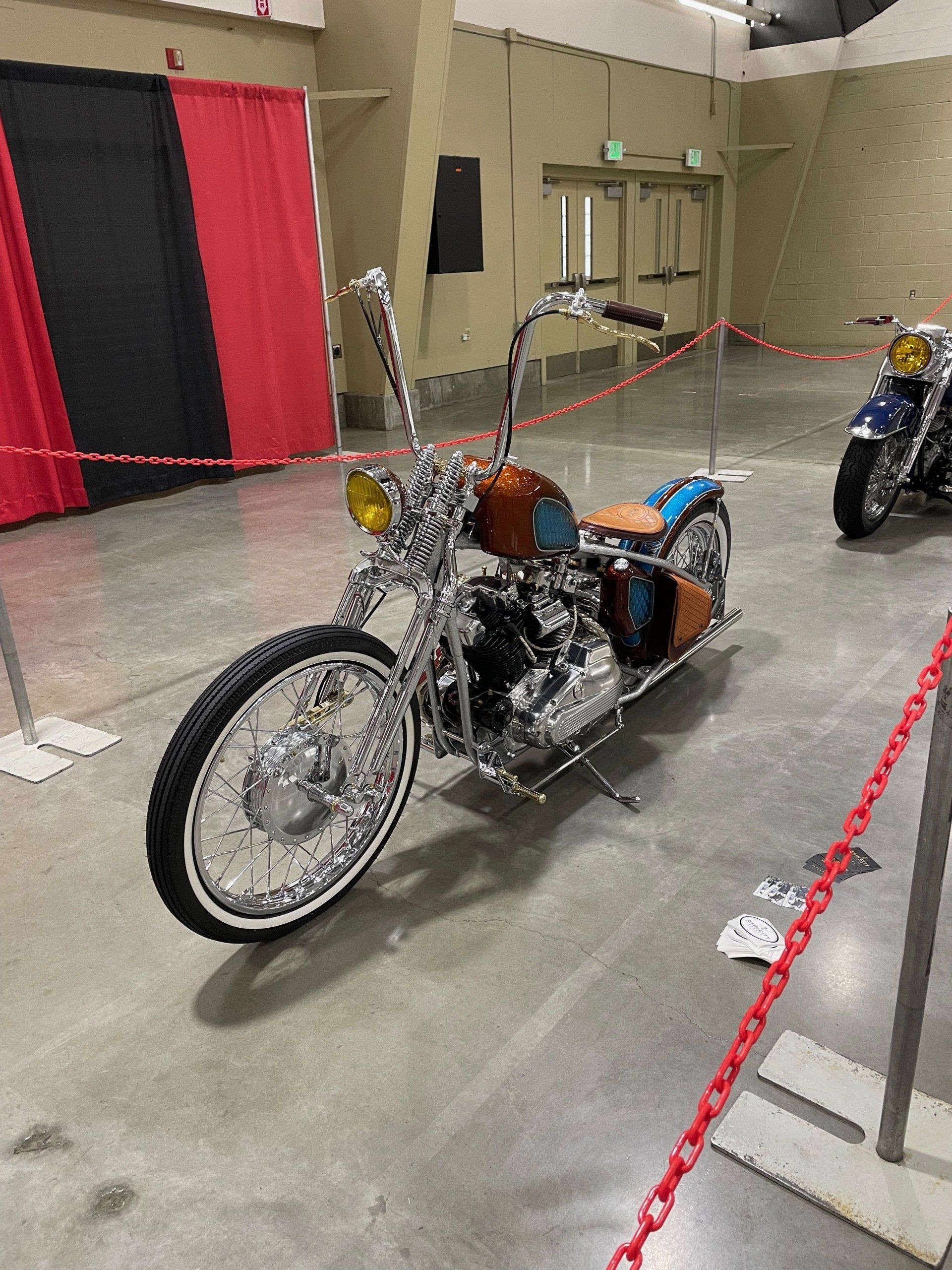 A motorcycle is parked in a room behind a chain link fence.
