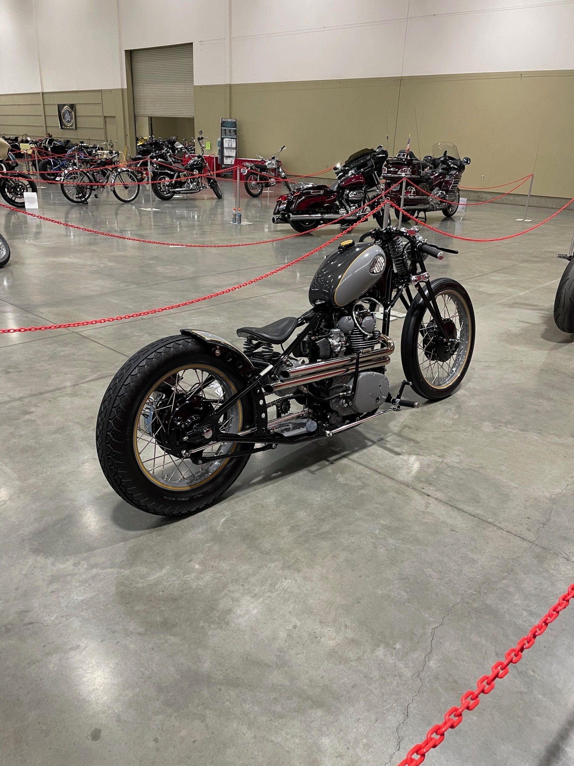 A motorcycle is parked in a warehouse next to a row of other motorcycles.