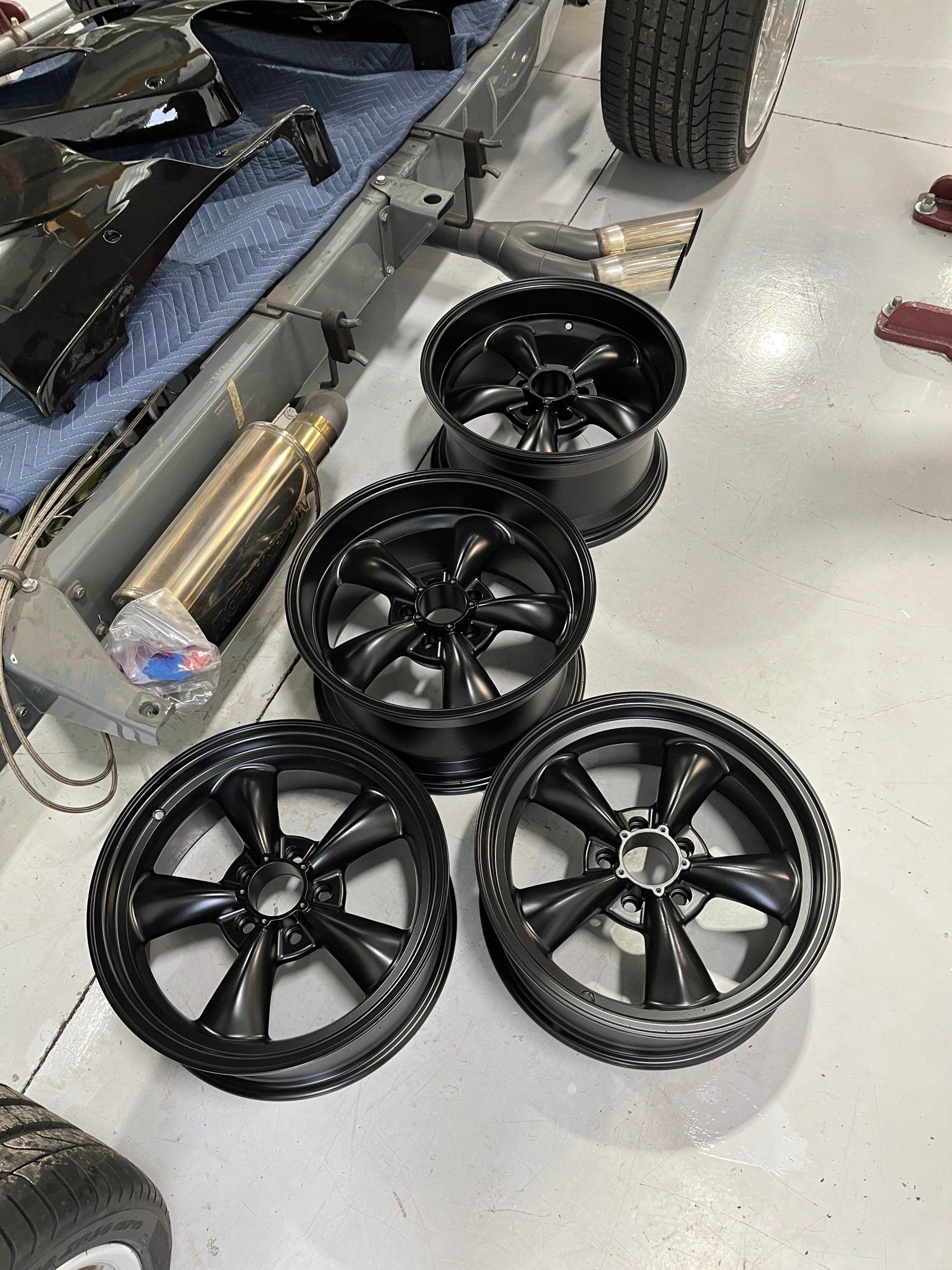 A bunch of black wheels are sitting on the floor in a garage.