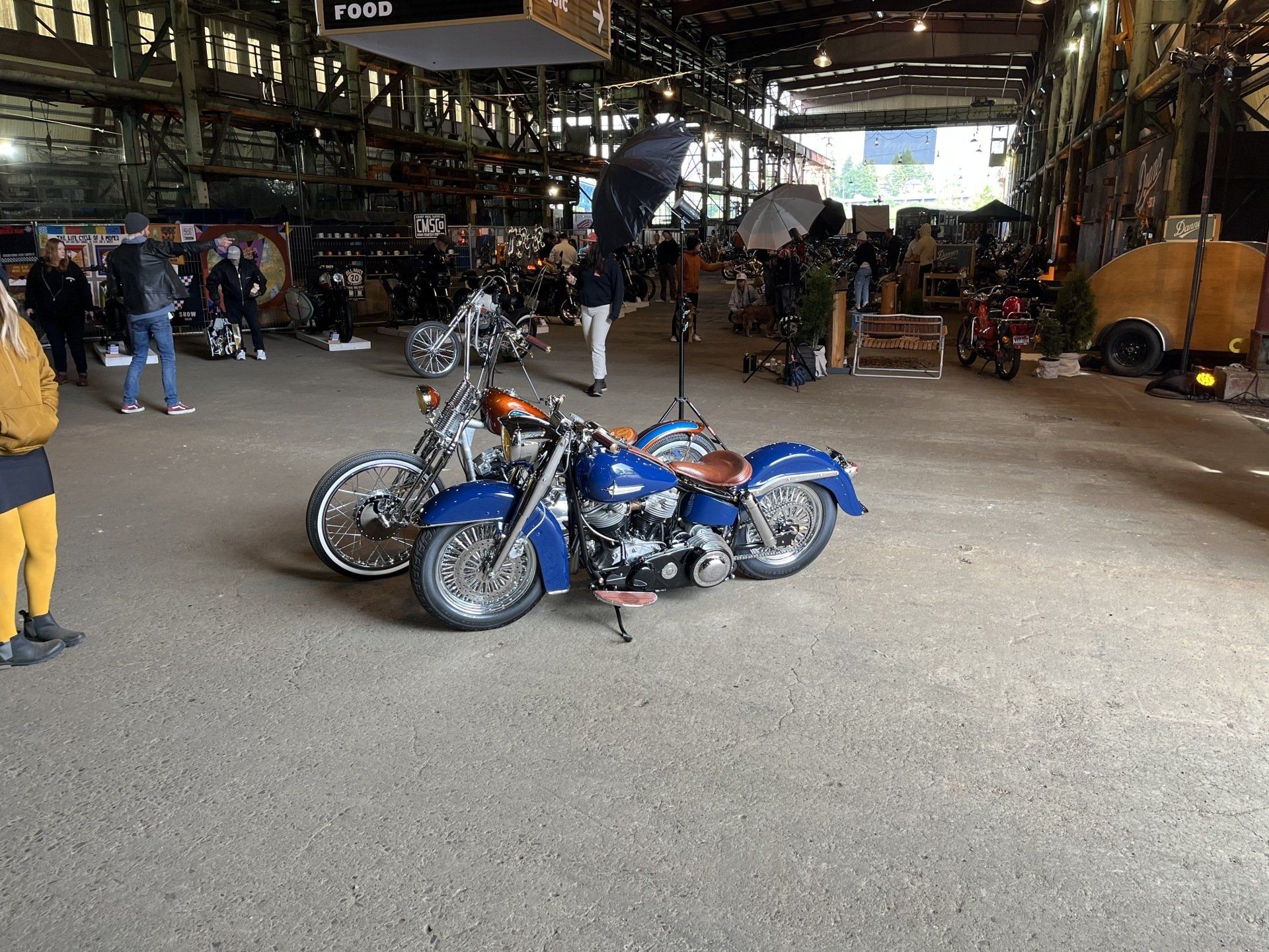Two blue motorcycles are parked in a large warehouse