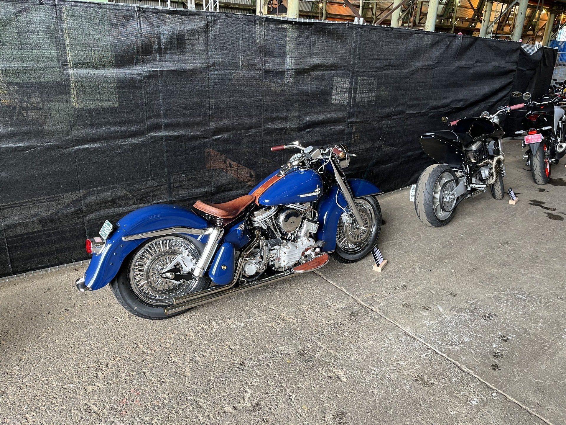 A blue motorcycle is parked next to a black fence.
