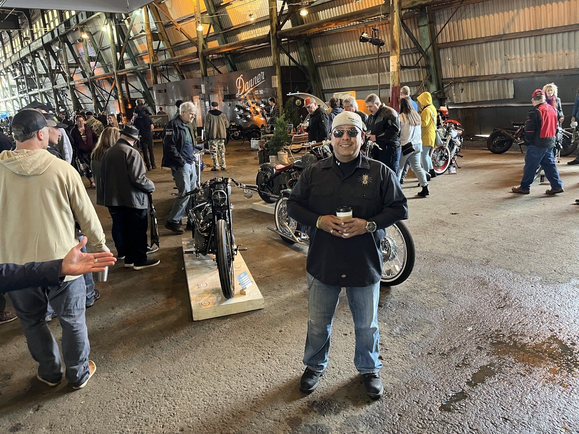 A man is standing in a warehouse surrounded by motorcycles.